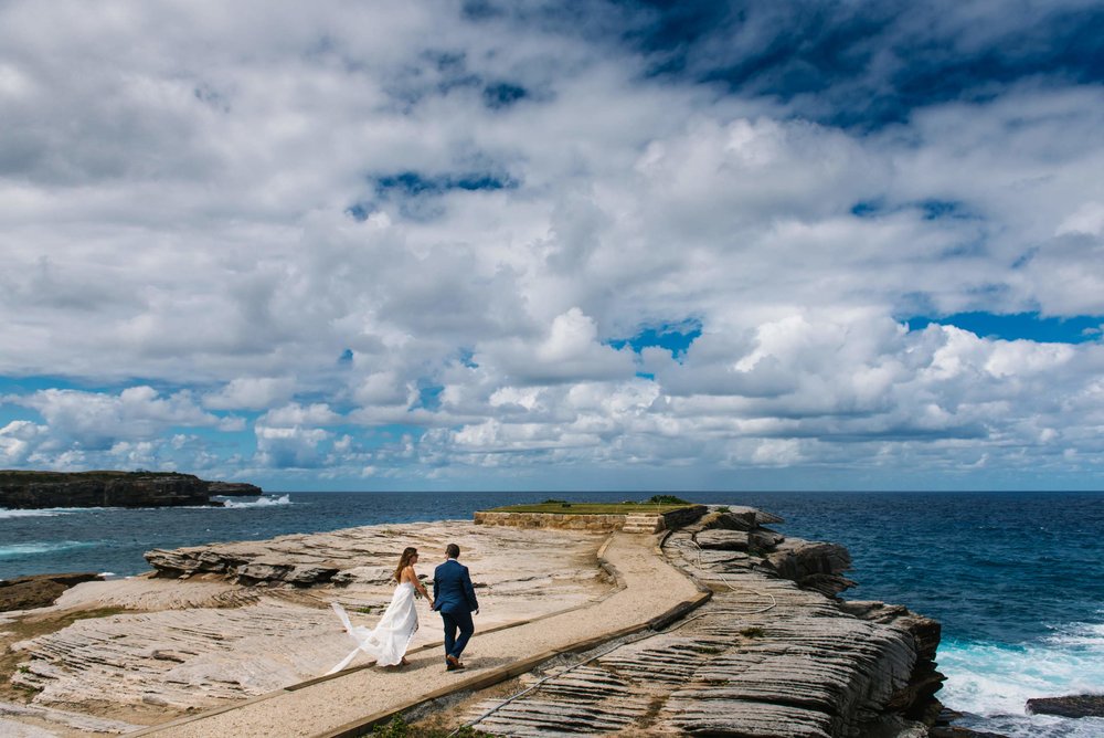 Bride and groom walking along outlook at Little Bay, NSW