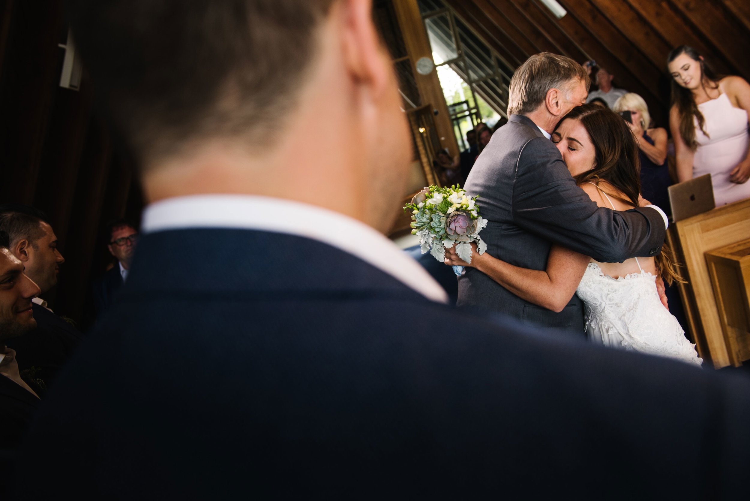 Bride hugs father as he gives her away to the groom 