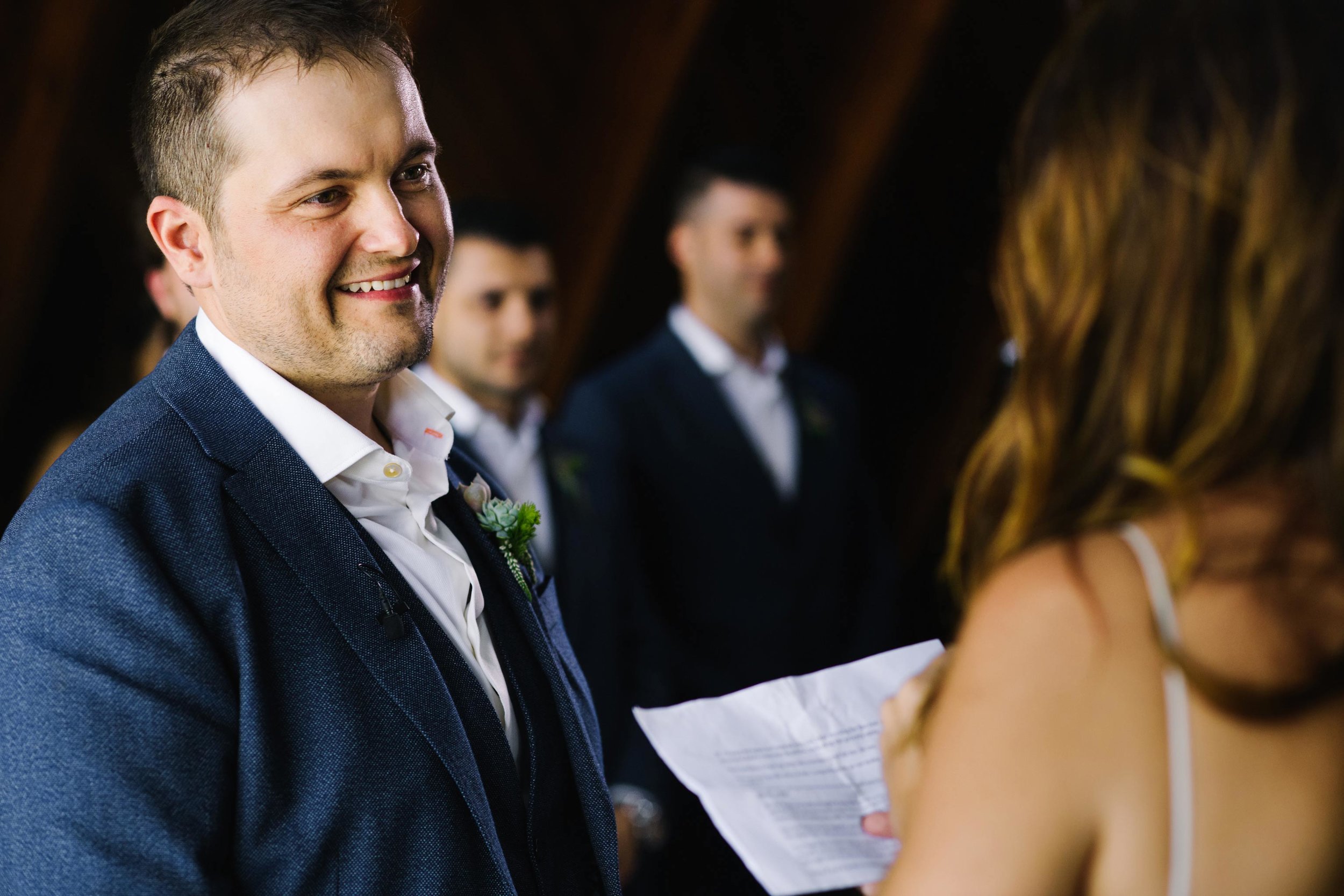 Groom smiles at bride during wedding ceremony
