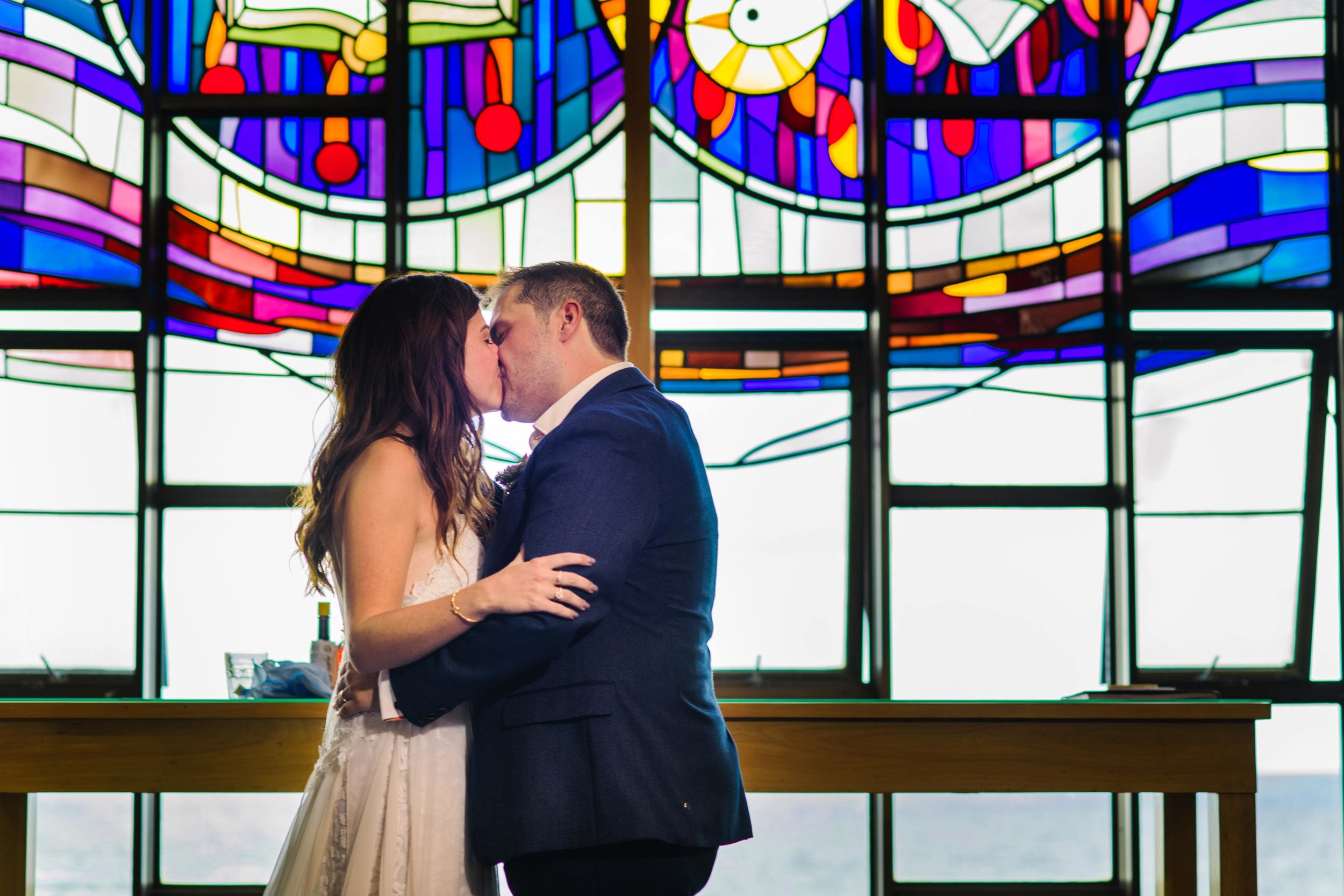 First kiss as husband and wife with stained glass windows in the background