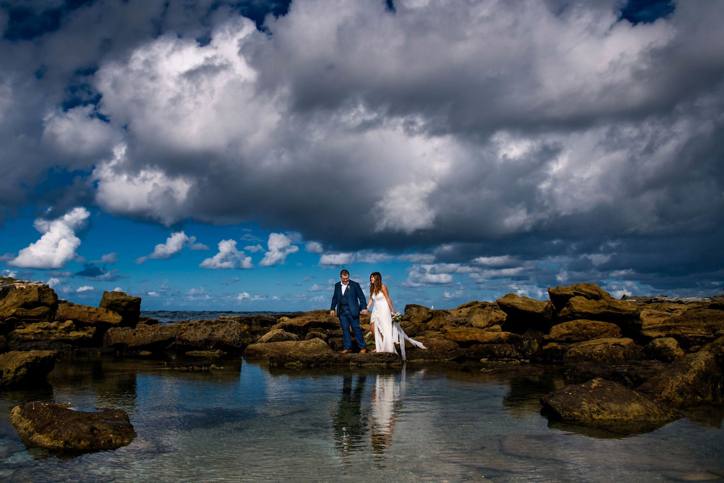 Newlyweds amongst rocks and shoreline at Little Bay