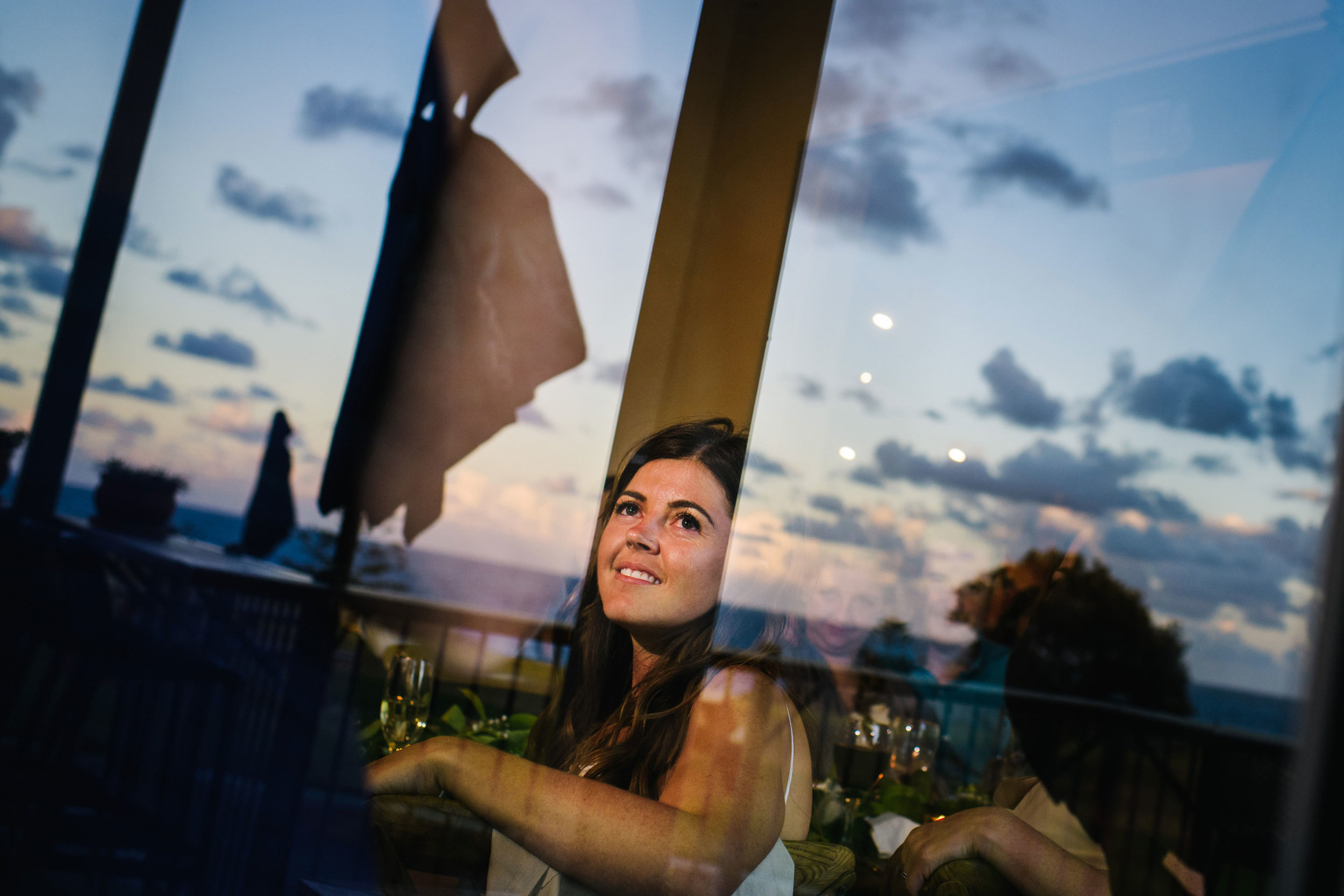 Bride smiling with the evening sky reflected in windows
