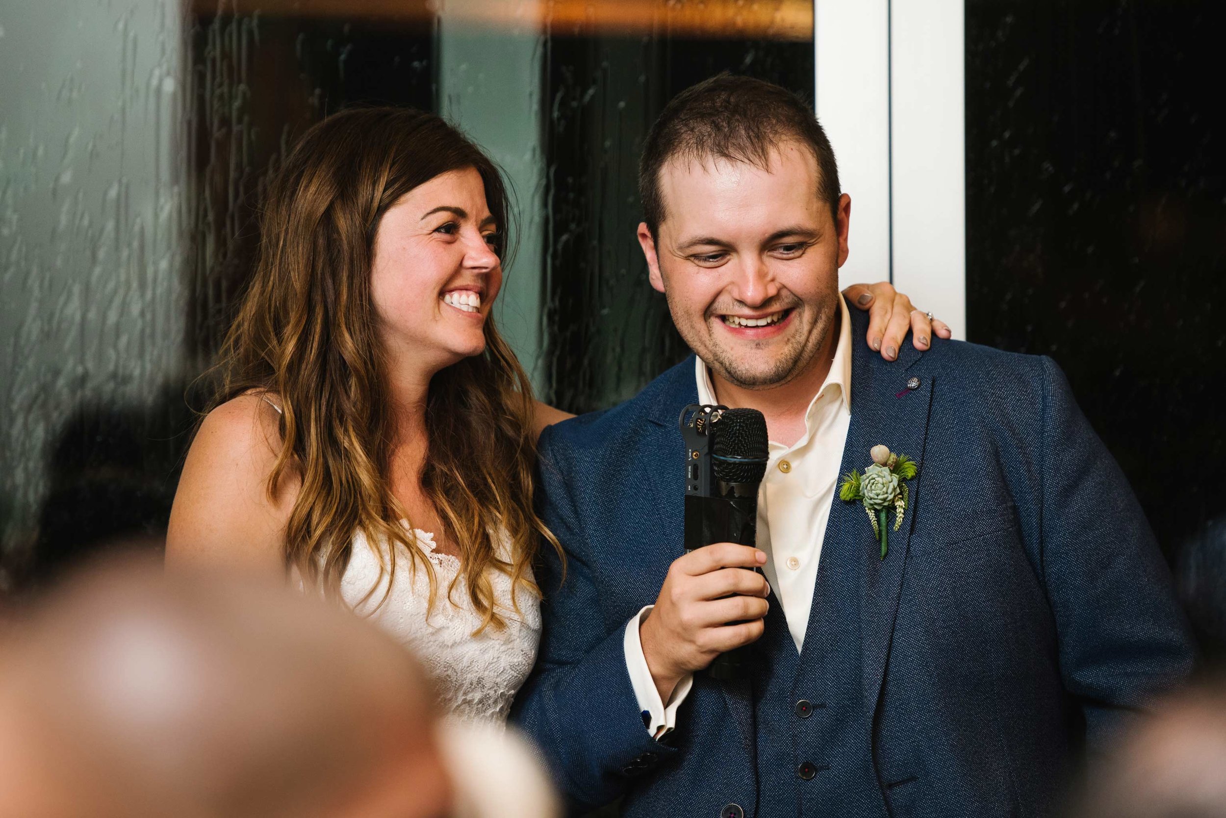 Newlyweds laughing during speeches
