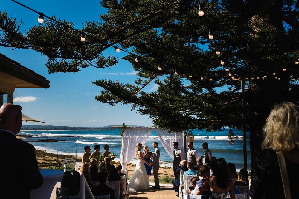 Wedding ceremony at Long Reef Golf Club on patio with beach in the background