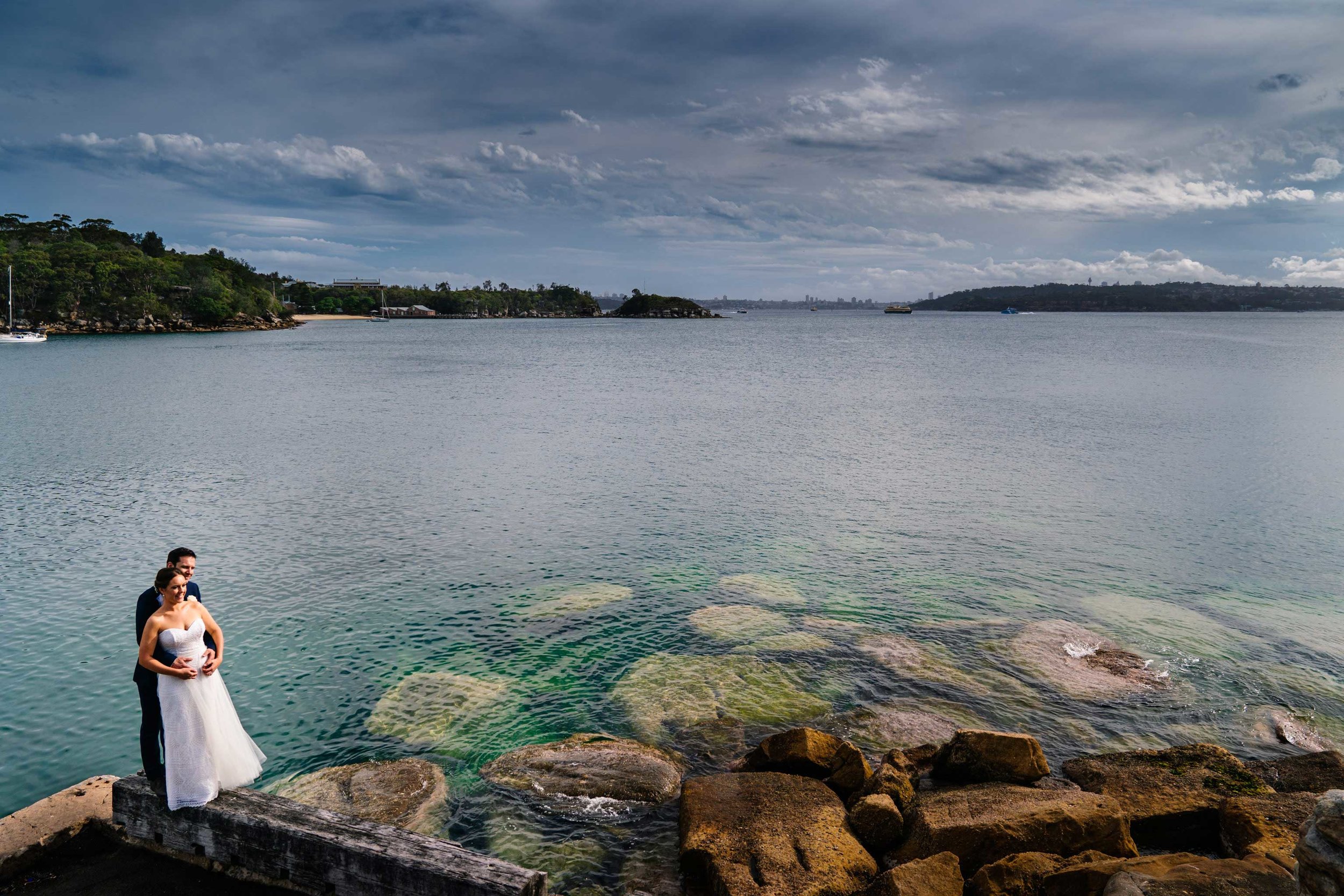 Bride and groom pose near the water at Little Manly Point