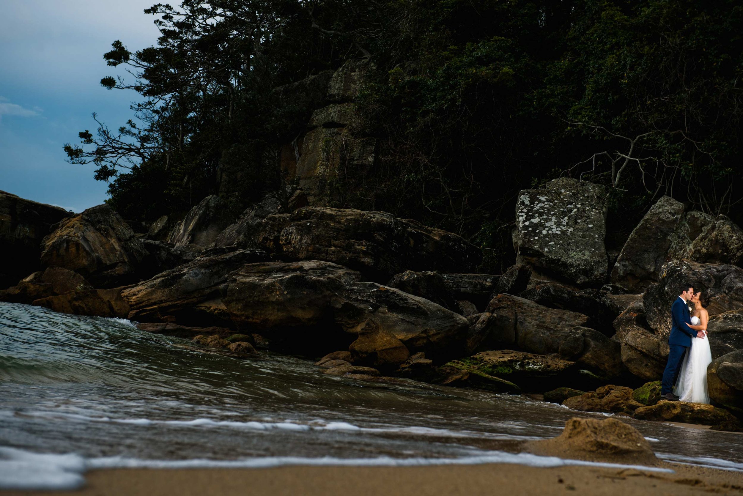 Bride and groom on rocks at Shelly Beach
