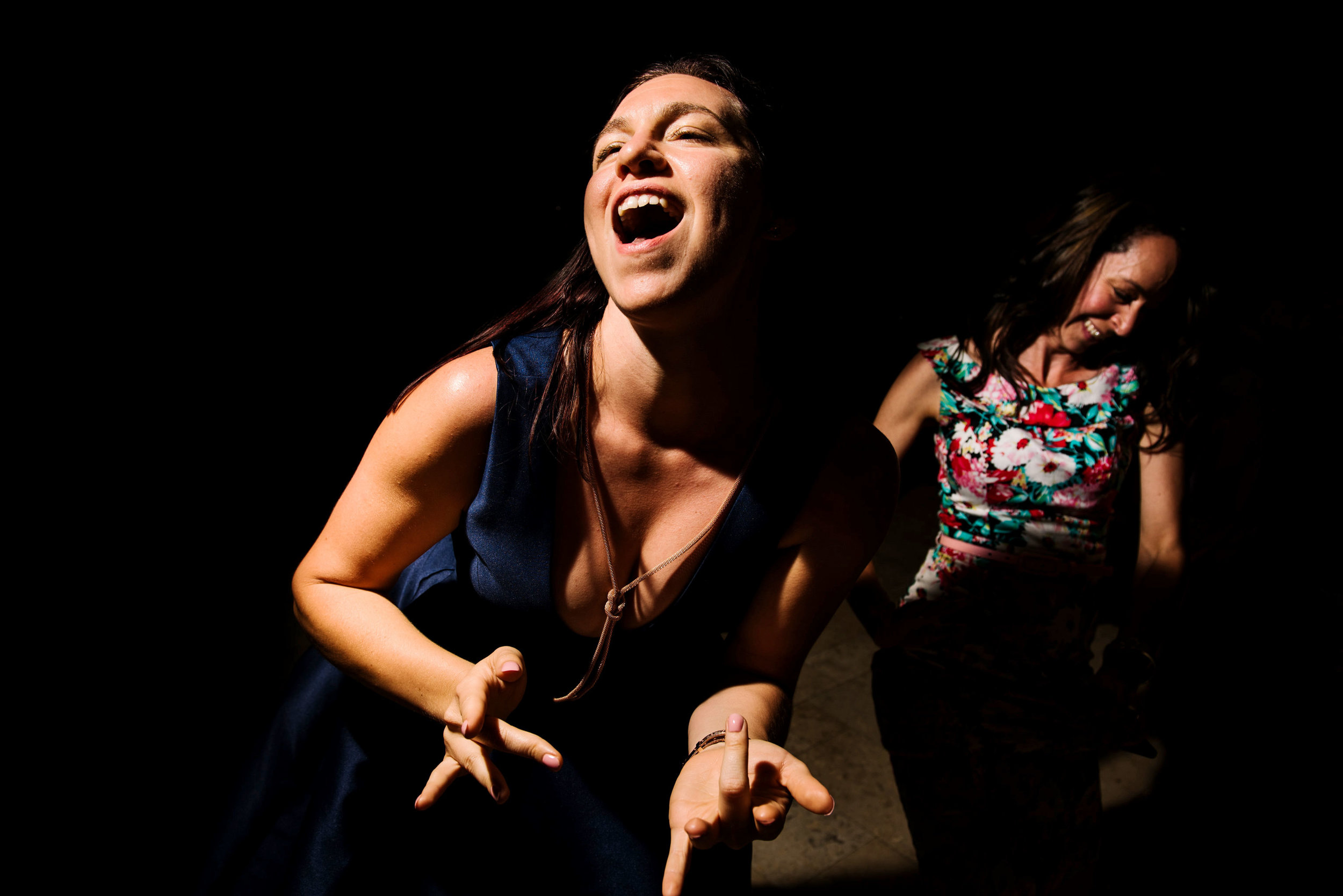 Woman laughing and playing air guitar at wedding reception