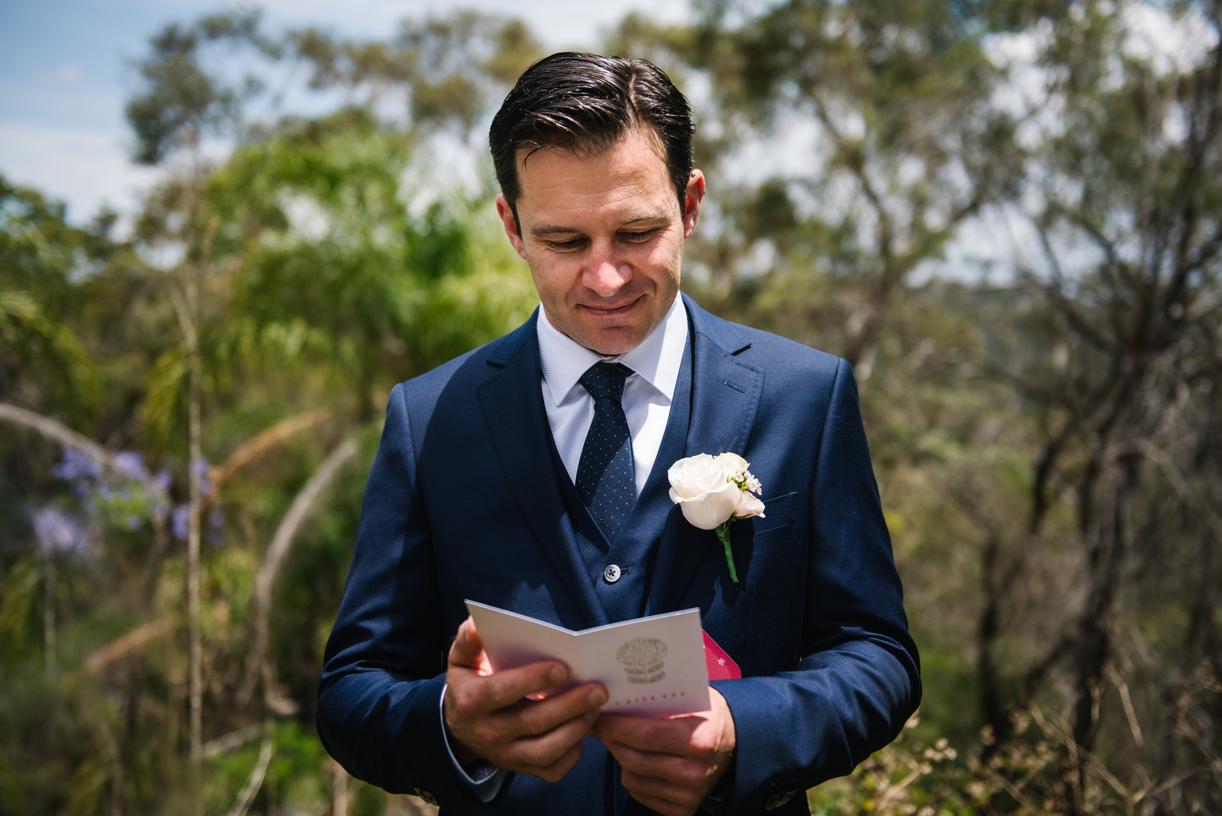 Groom reading card from bride on wedding day