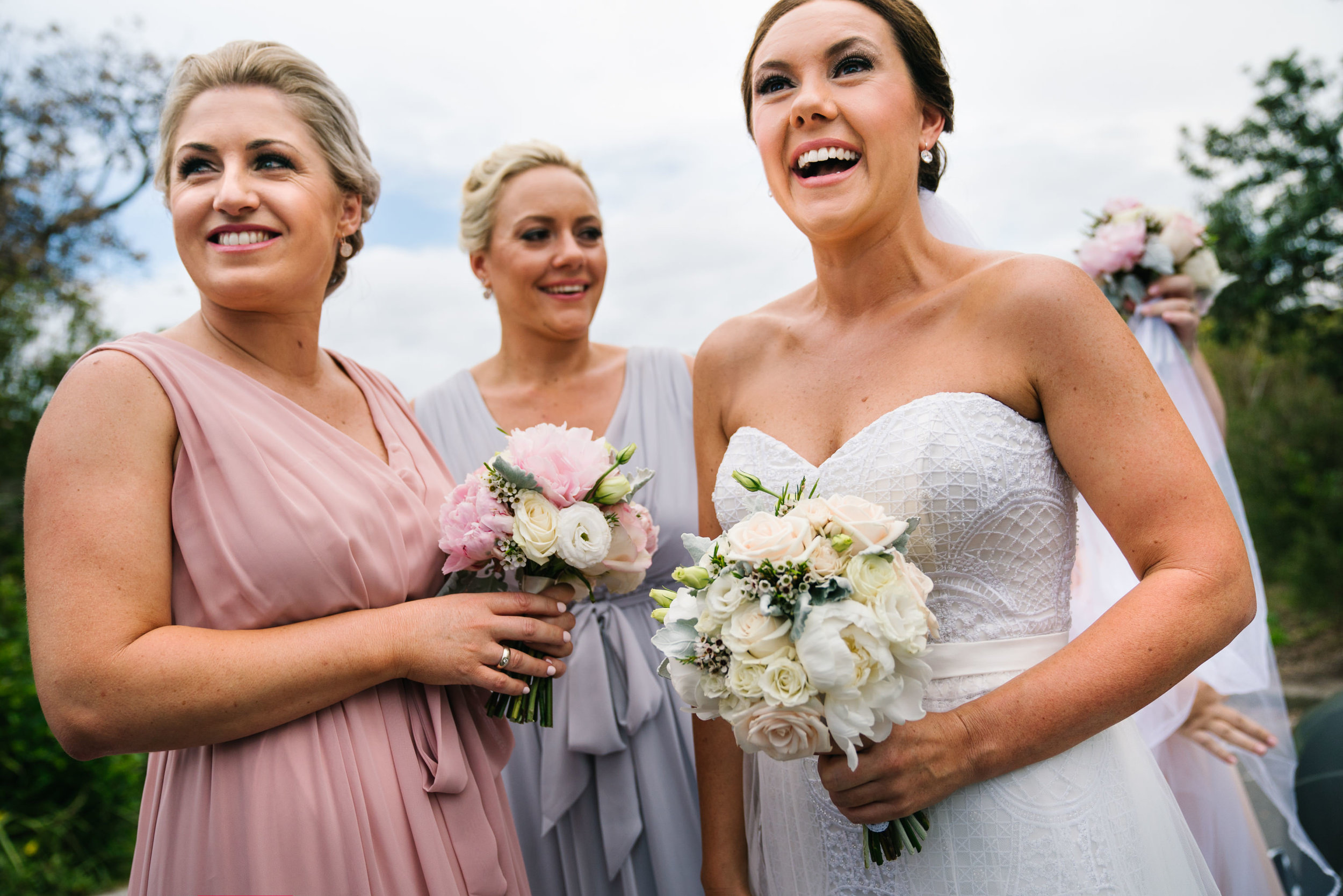 Bride laughing with bridesmaids before wedding ceremony at Shelly Beach