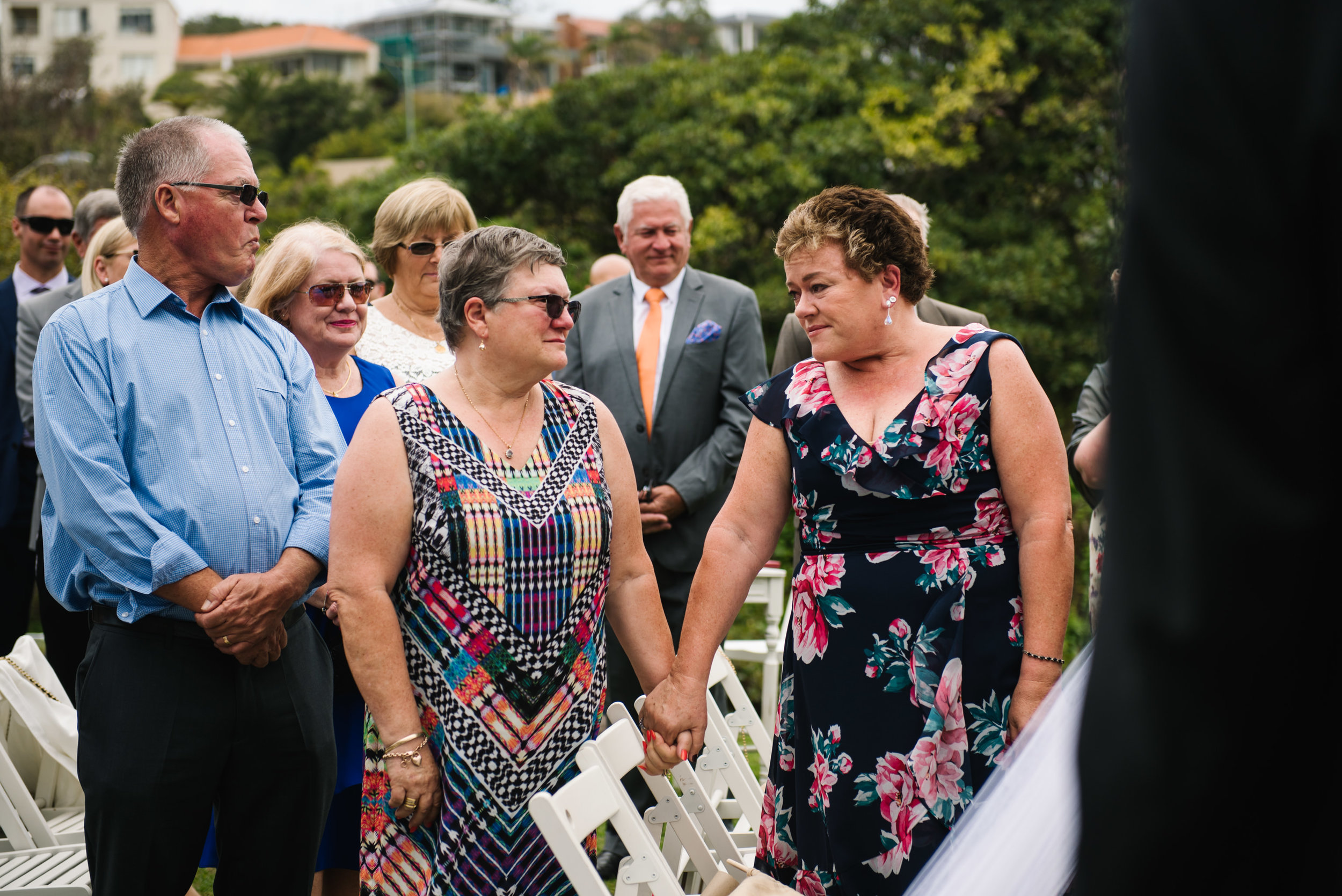 Mother of bride and aunt exchanging emotional look as bride walks down aisle