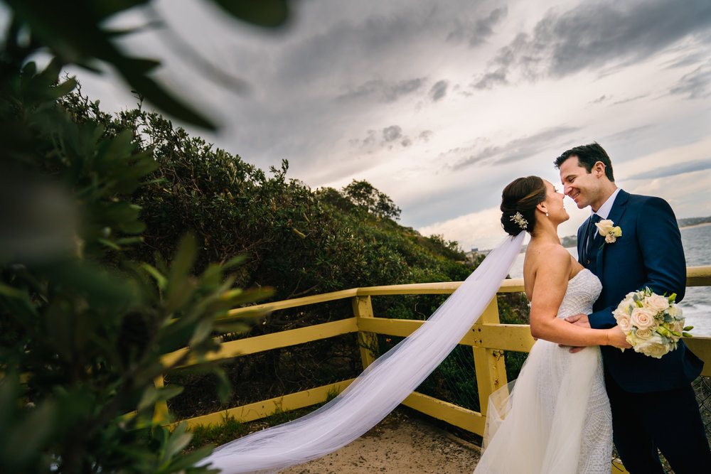 Newlyweds embracing with view of ocean in the backdrop