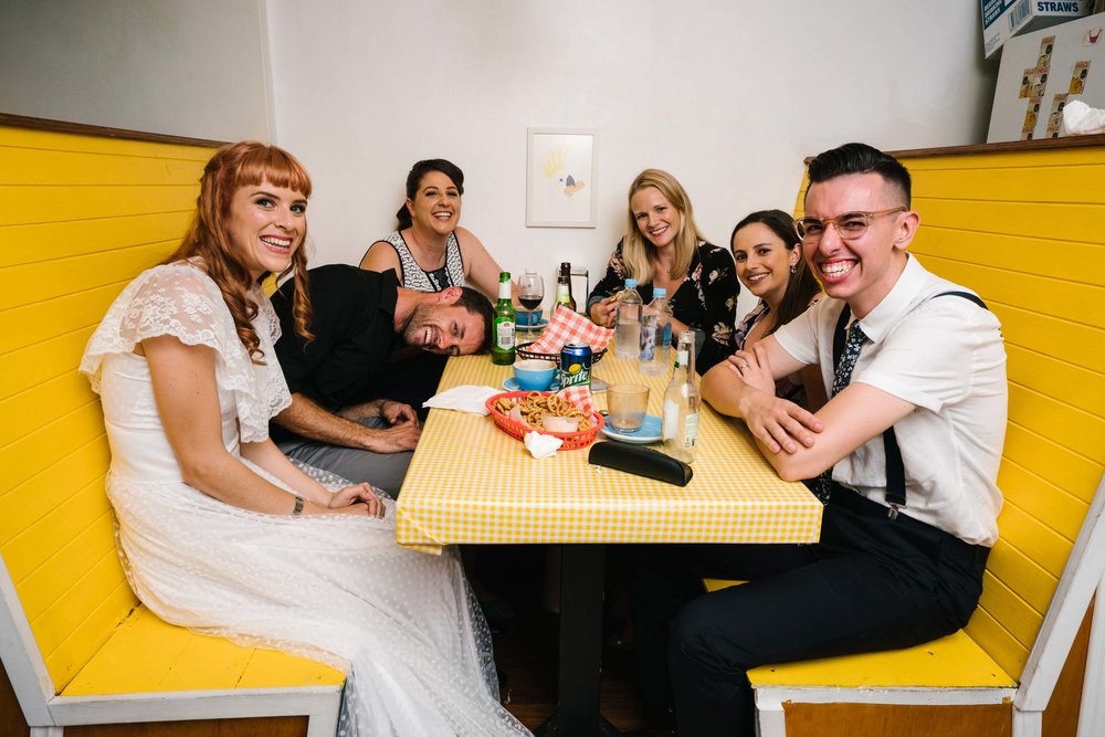 Newlyweds with guests in booth at retro wedding reception