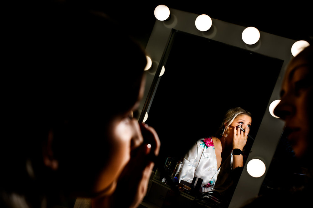 View of bride in mirror getting makeup done before wedding