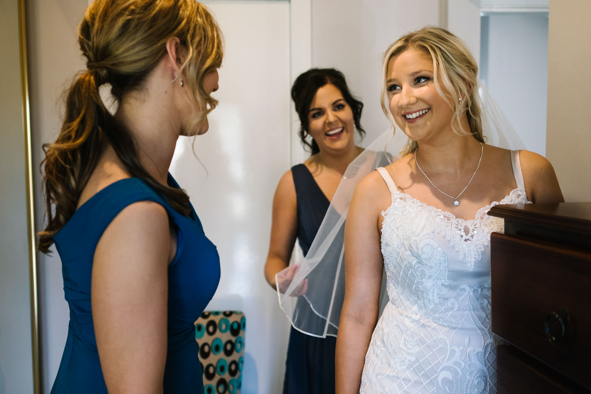Bride smiling as bridesmaids help her get dressed