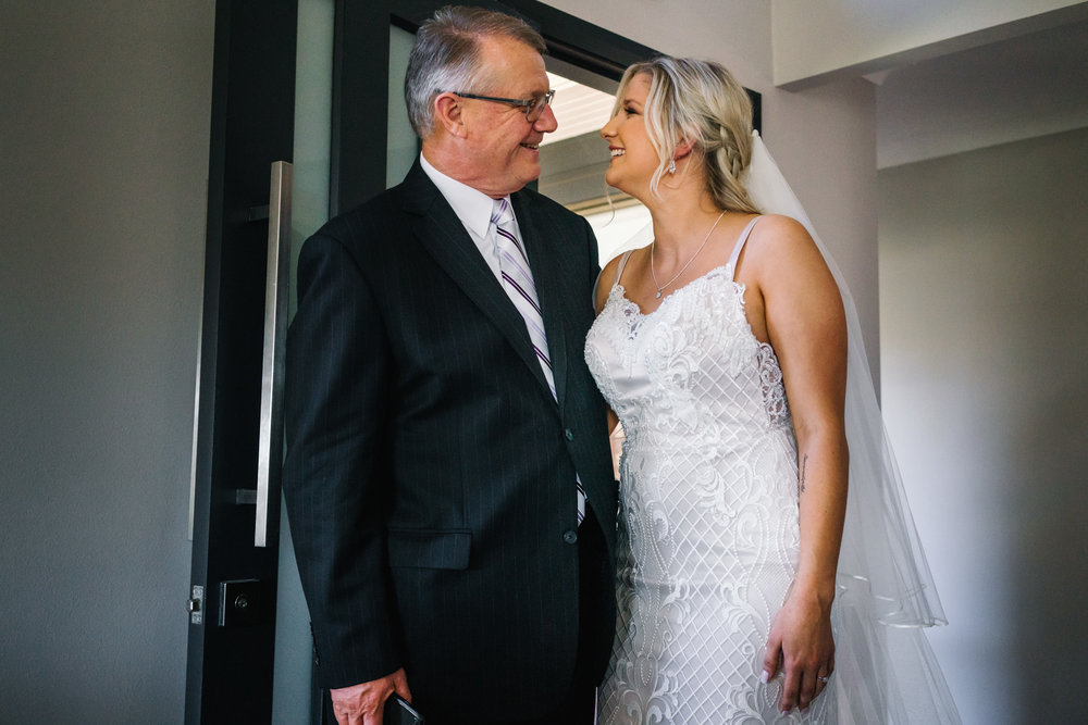 Bride and father hugging and smiling in family home