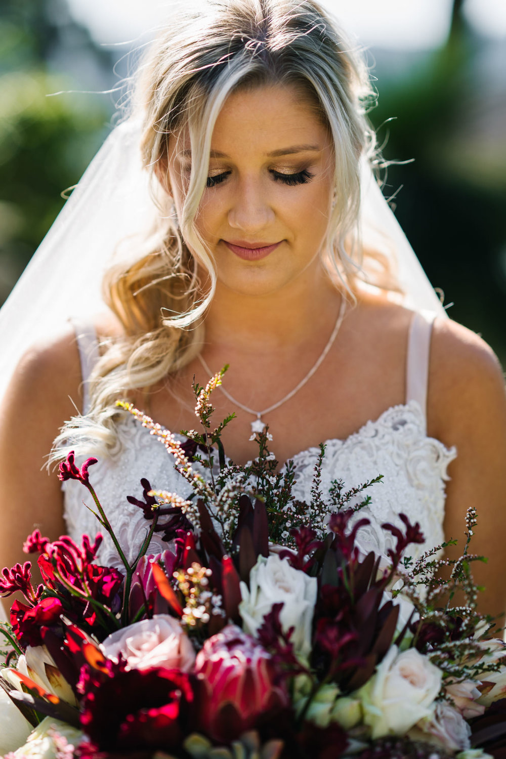 Bride holding bouquet with proteas, roses and kangaroo paw