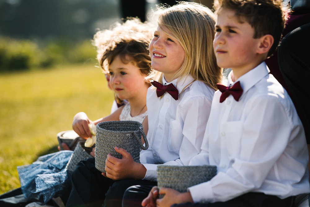 Ring bearer in bowtie smiling as he watches the ceremony 