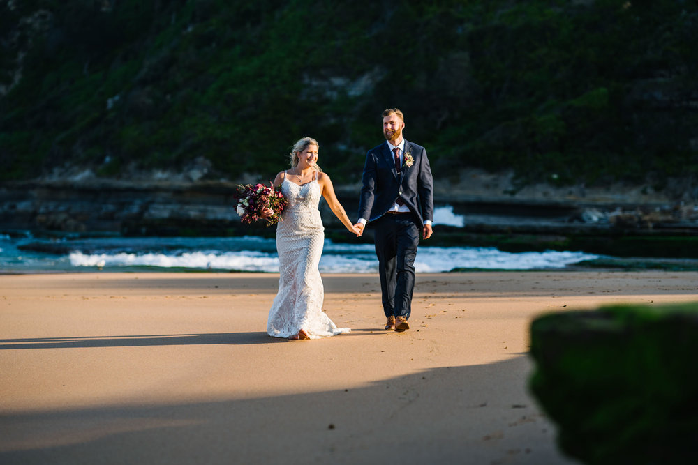 Bride and groom walking up the beach after Northern Beaches wedding