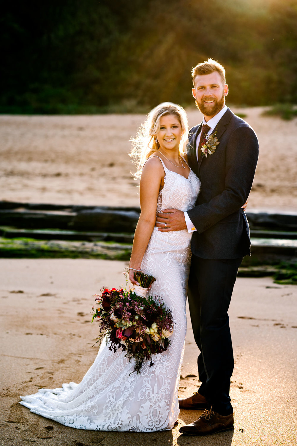 Young bride and groom posing on Turimetta beach