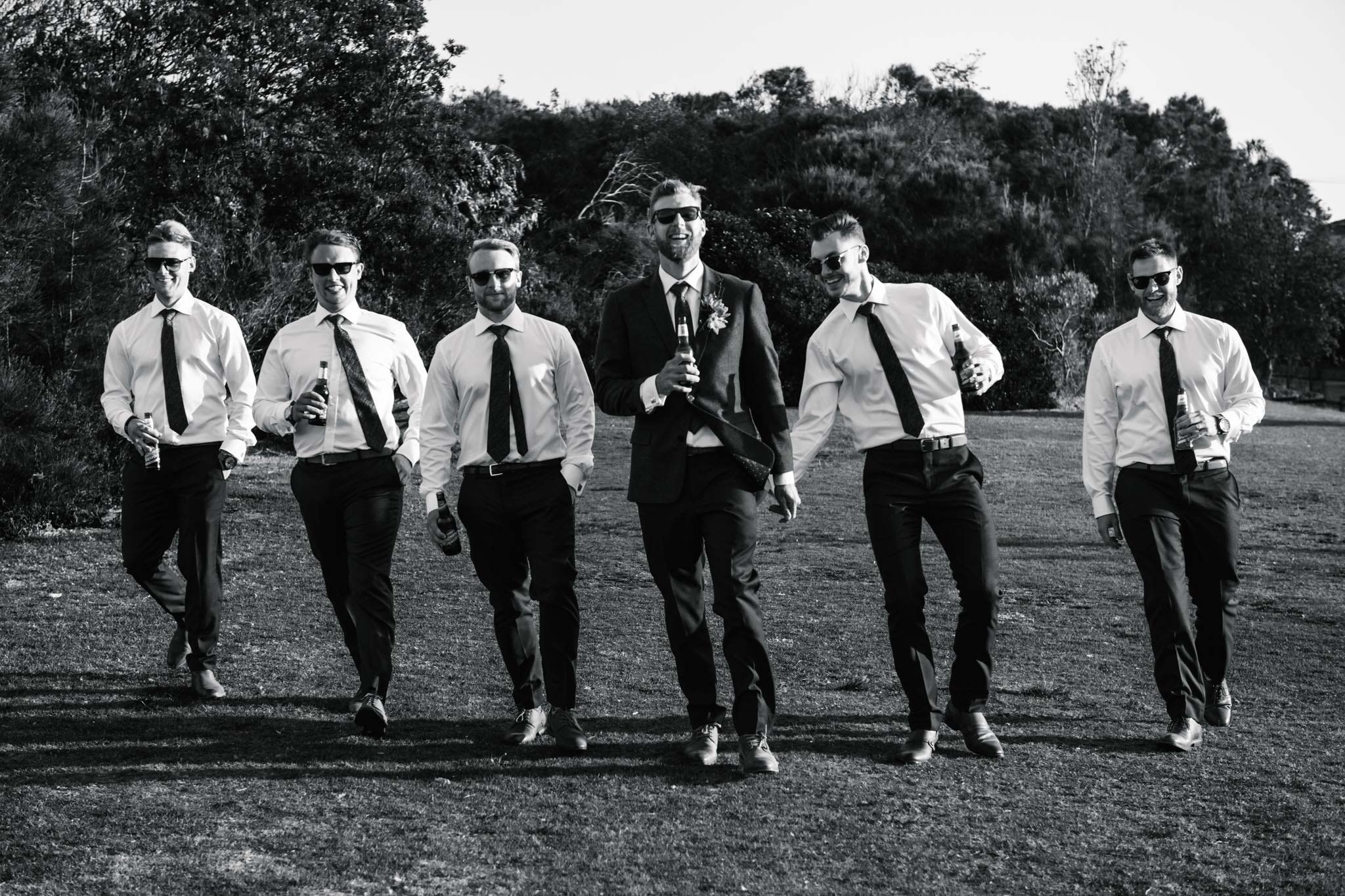 Groom and groomsmen walking, while one of the groomsmen slaps the groom on the butt