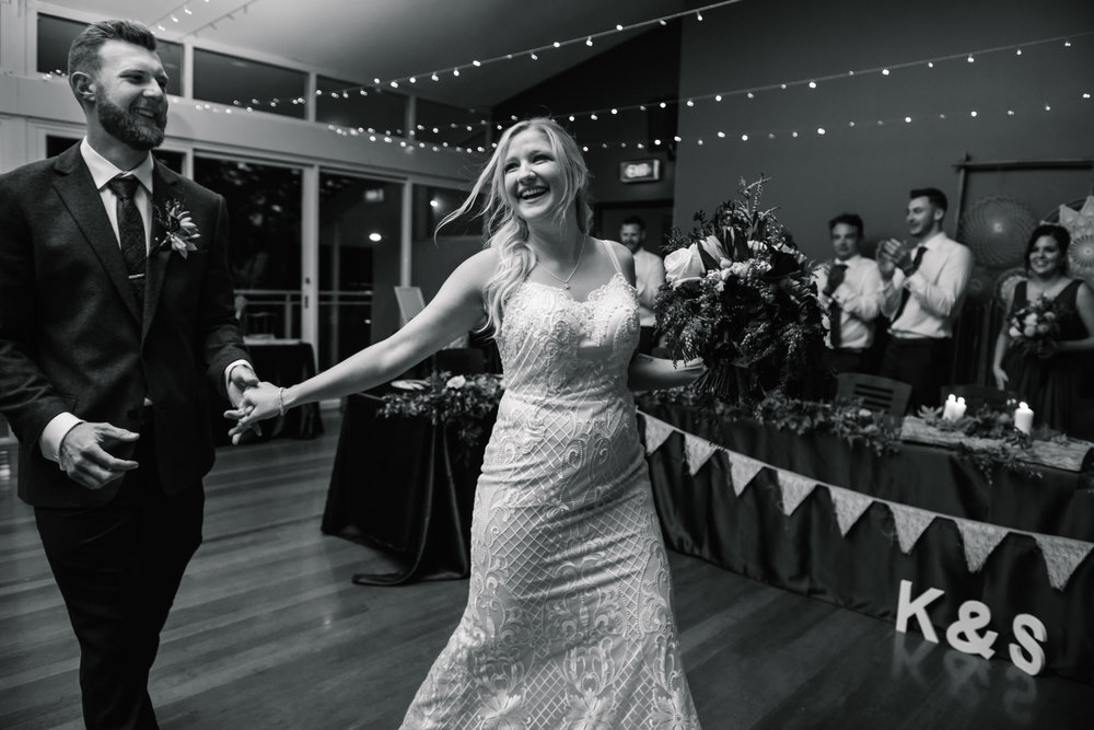 Newlyweds looking happy as they enter their wedding reception