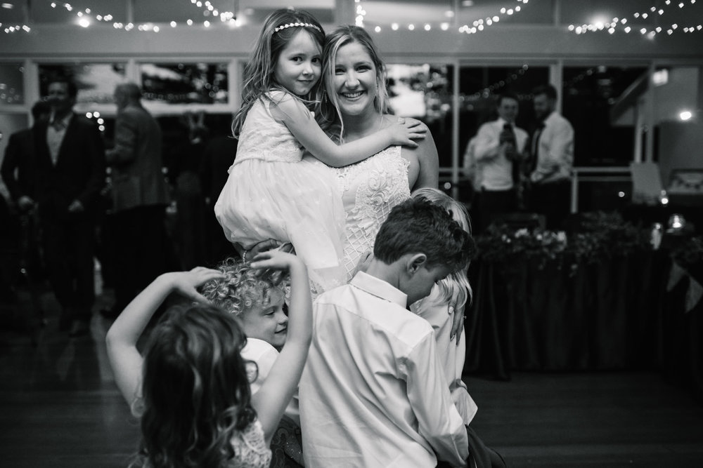 Bride being embraced by all the children attending her wedding