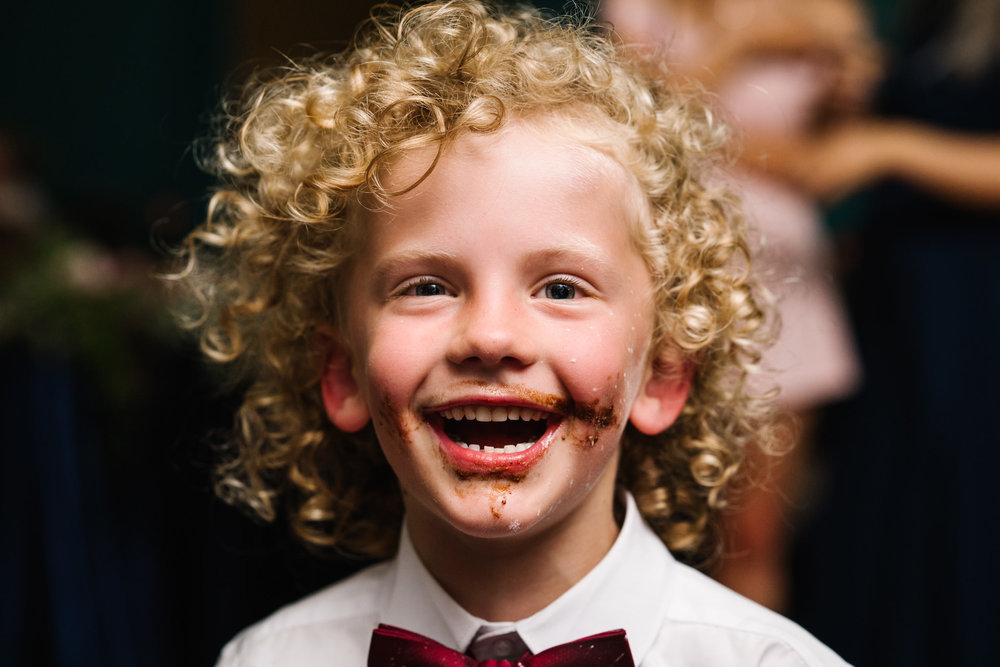 Ring bearer with chocolate wedding cake all over his face