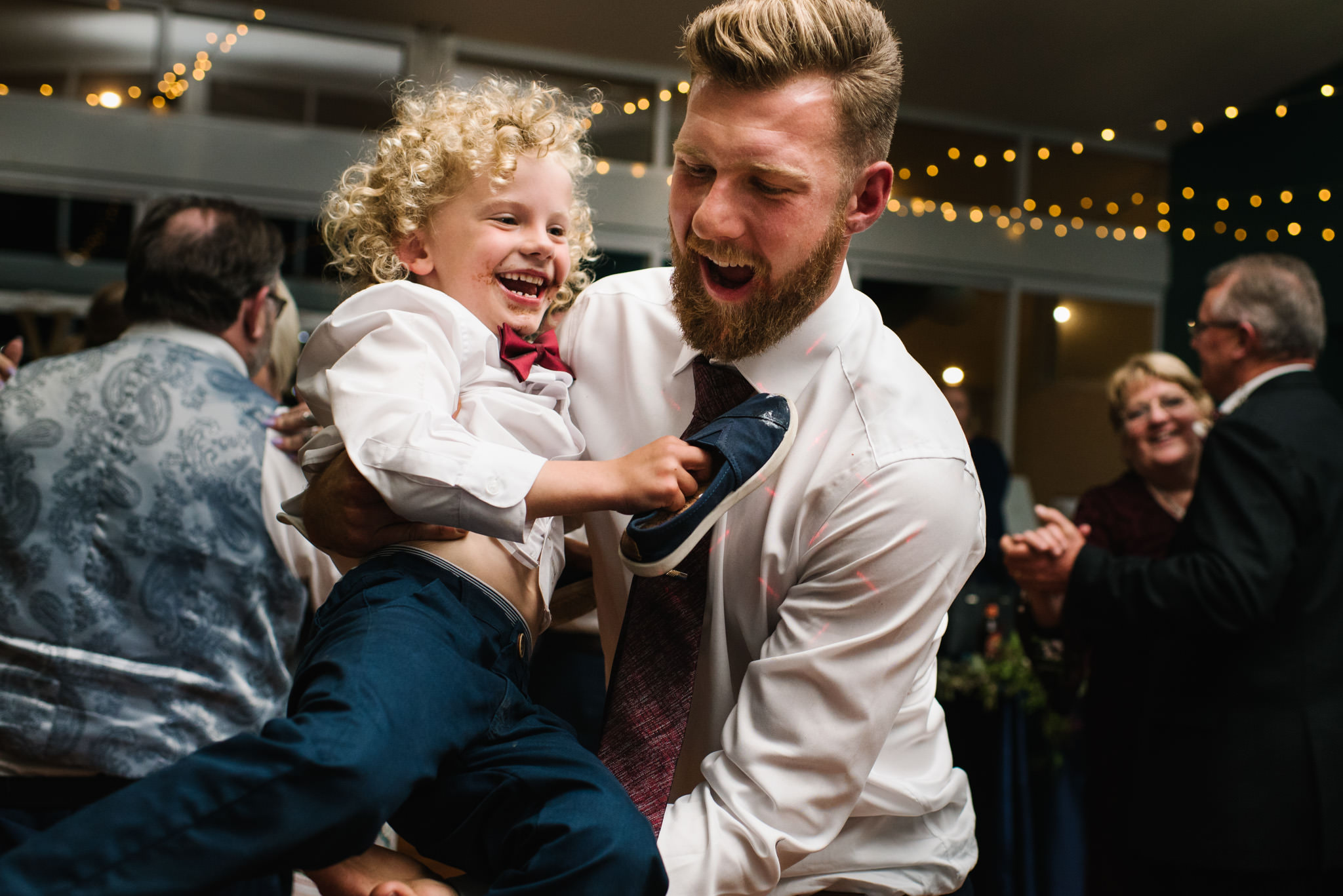 Groom playing with ring bearer both laughing