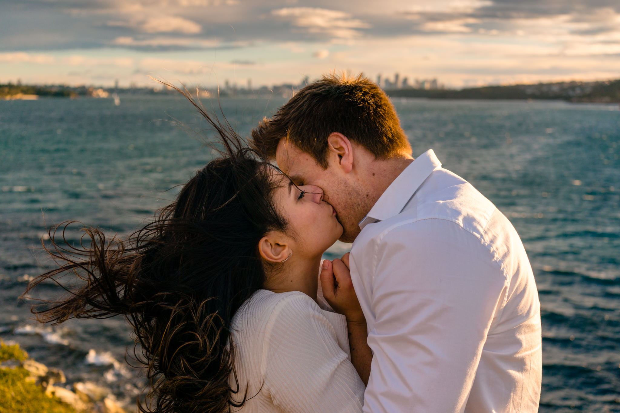 Couple kiss on windy cliff at Watsons Bay