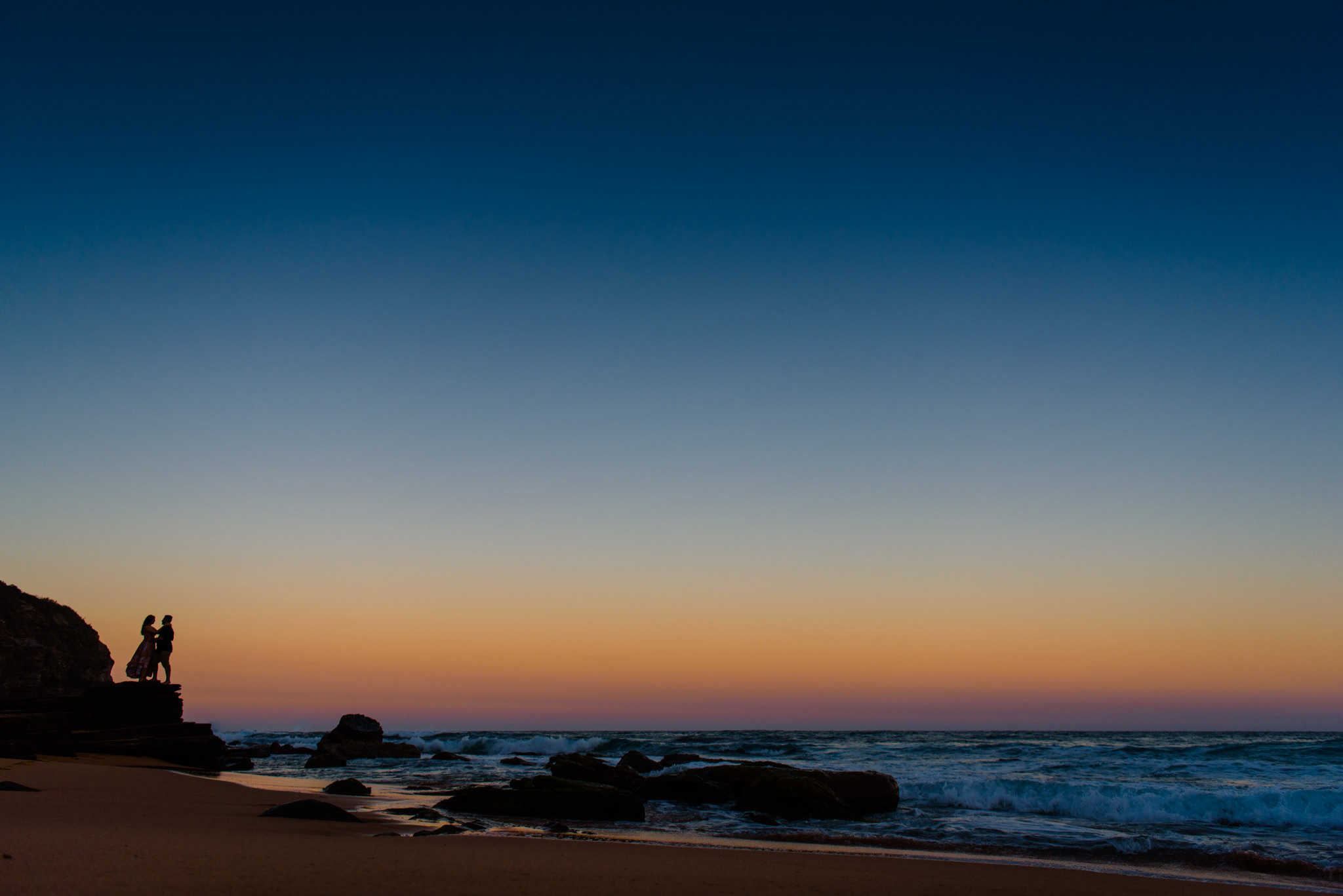Silhouette of couple against bright sunset colours at Turimetta Beach