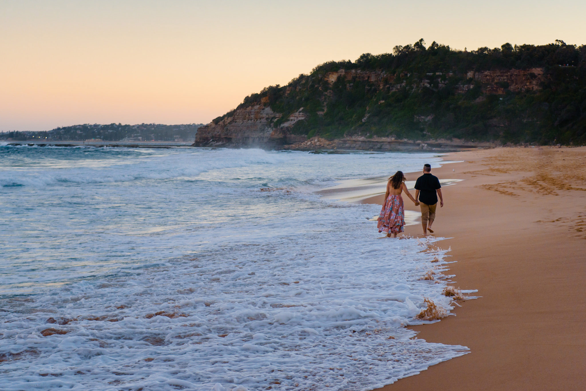 Couple walking along the beach during Northern Beaches engagement session