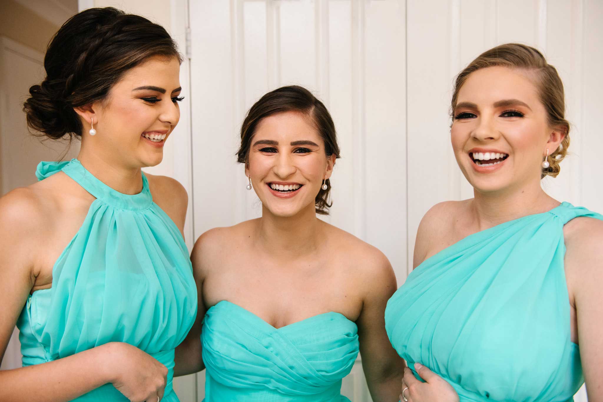 Smiling bridesmaids laugh as they are getting ready for the wedding day