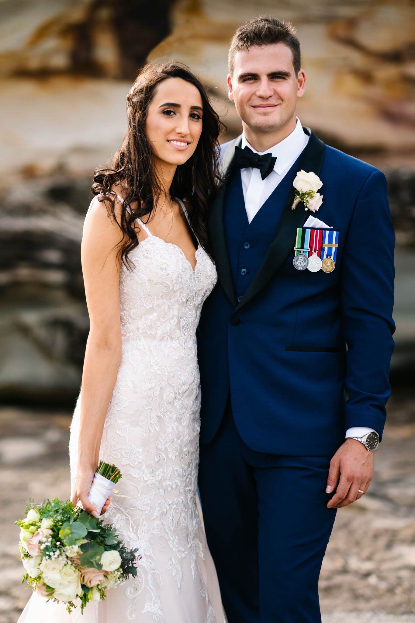 Bride and groom posing in front of rock face at Freshwater