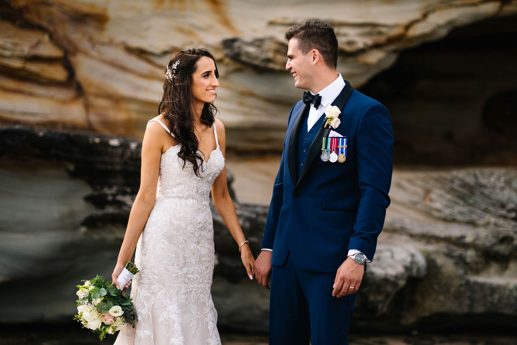 Newlyweds laughing and holding hands during bridal portraits on the Northern Beaches
