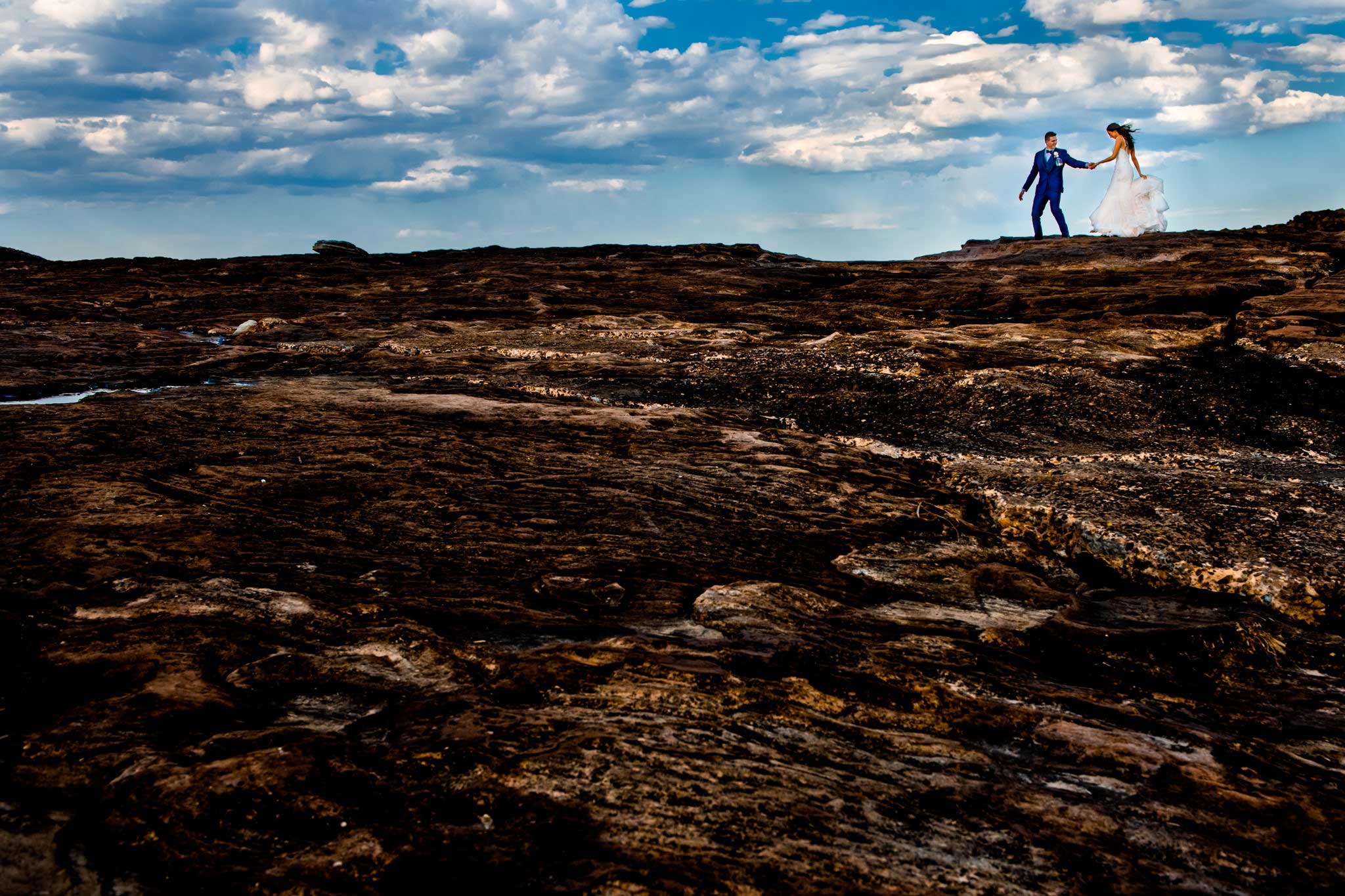 Newlyweds walking along moon-like rocks at Freshwater beach