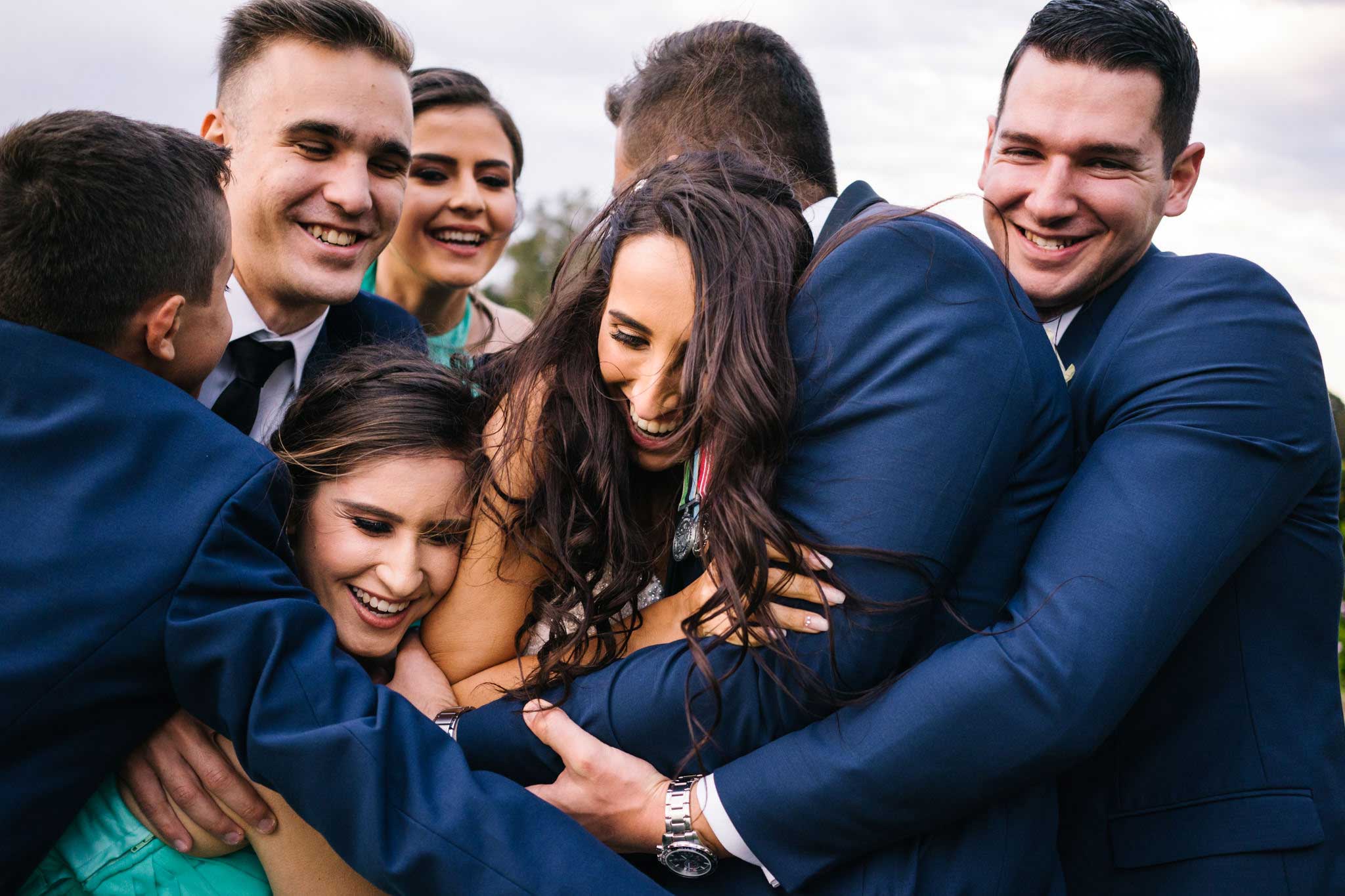 Bridal party embracing newlywed couple at Manly Golf Course