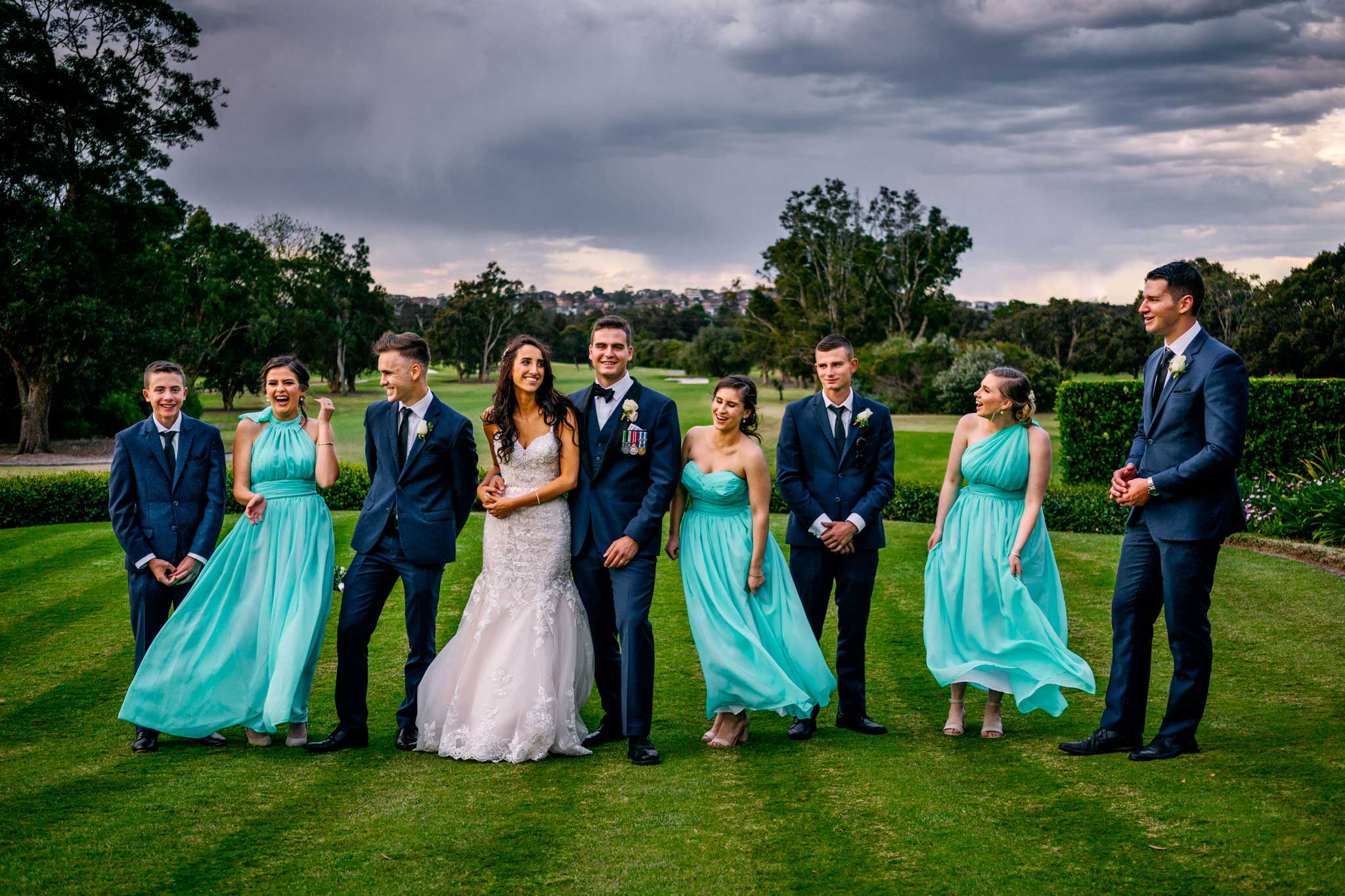 Bridal party laughing and playing on golf greens at Manly Golf Club
