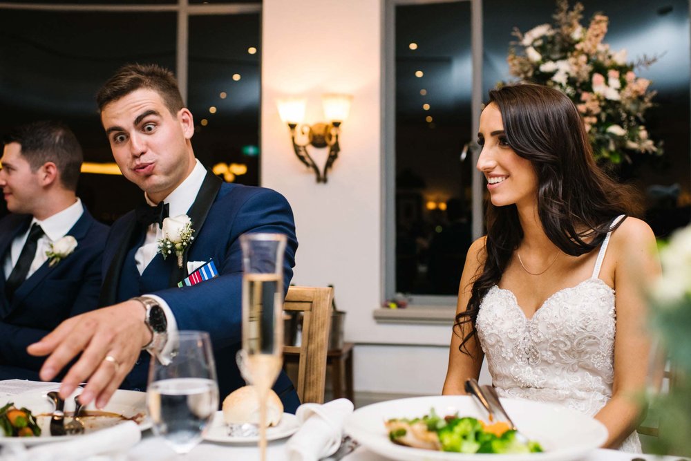 Groom makes a funny face as he reaches for his first drink at wedding reception