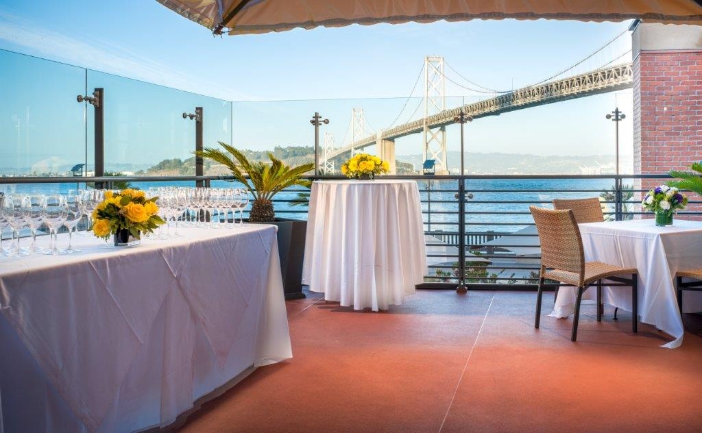 photo of outside private dining balcony in evening with view of the bay and Bay Bridge in background