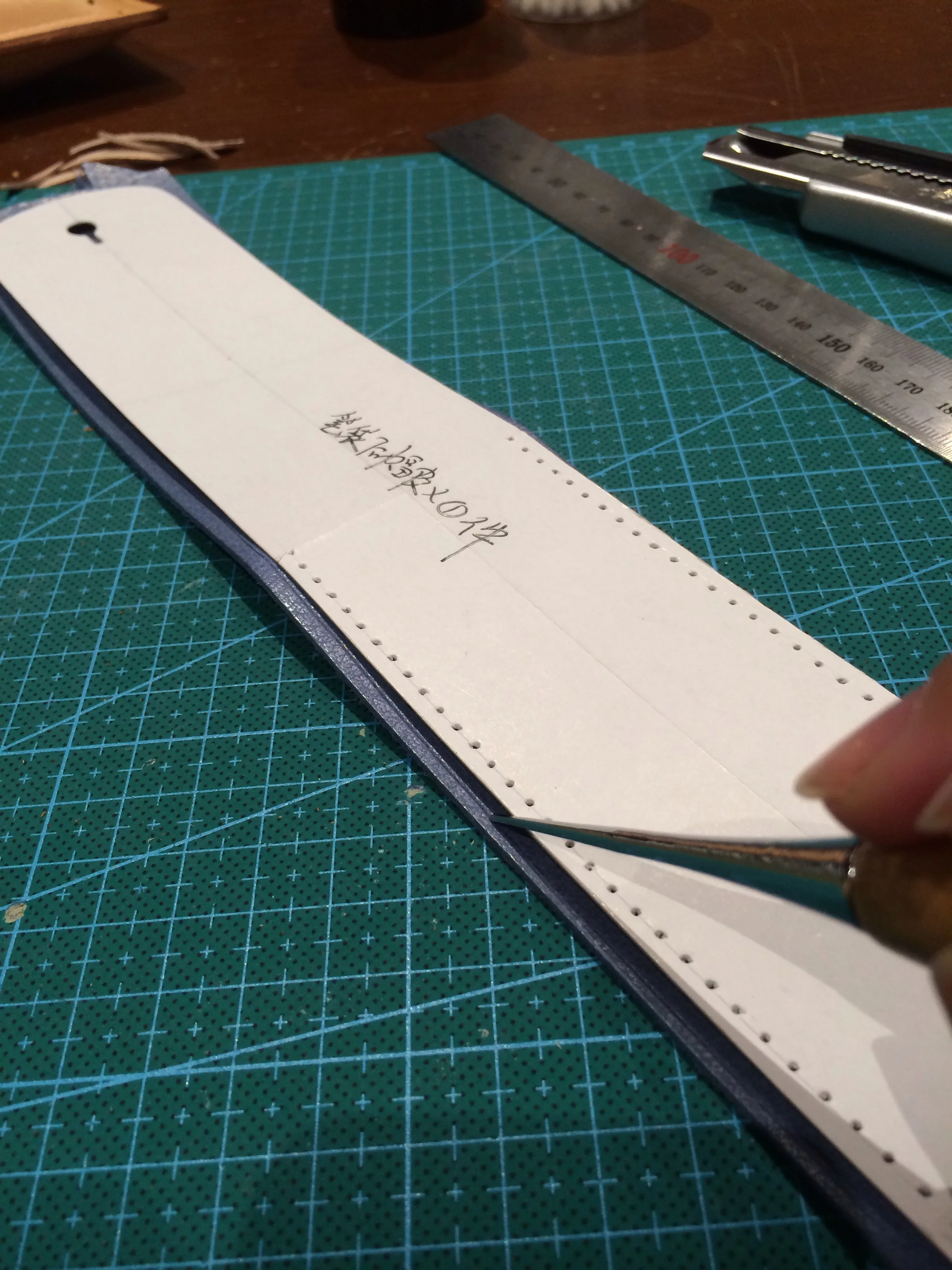 Tracing of the paper patterns using a metal tool with rounded tip. After scoring a line, we use a knife to cut the pattern out. Best to cut within the scored line, otherwise your leather will be bigger than the paper pattern.