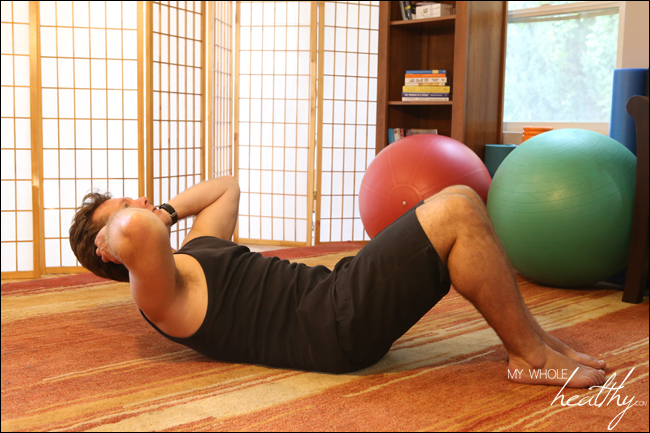 How to do a crunch correctly. Fingers light on the back of the head, abs fully engaged, feet remaining flat on the floor, shoulders lifted slightly off the floor. It is not a big or exaggerated movement.