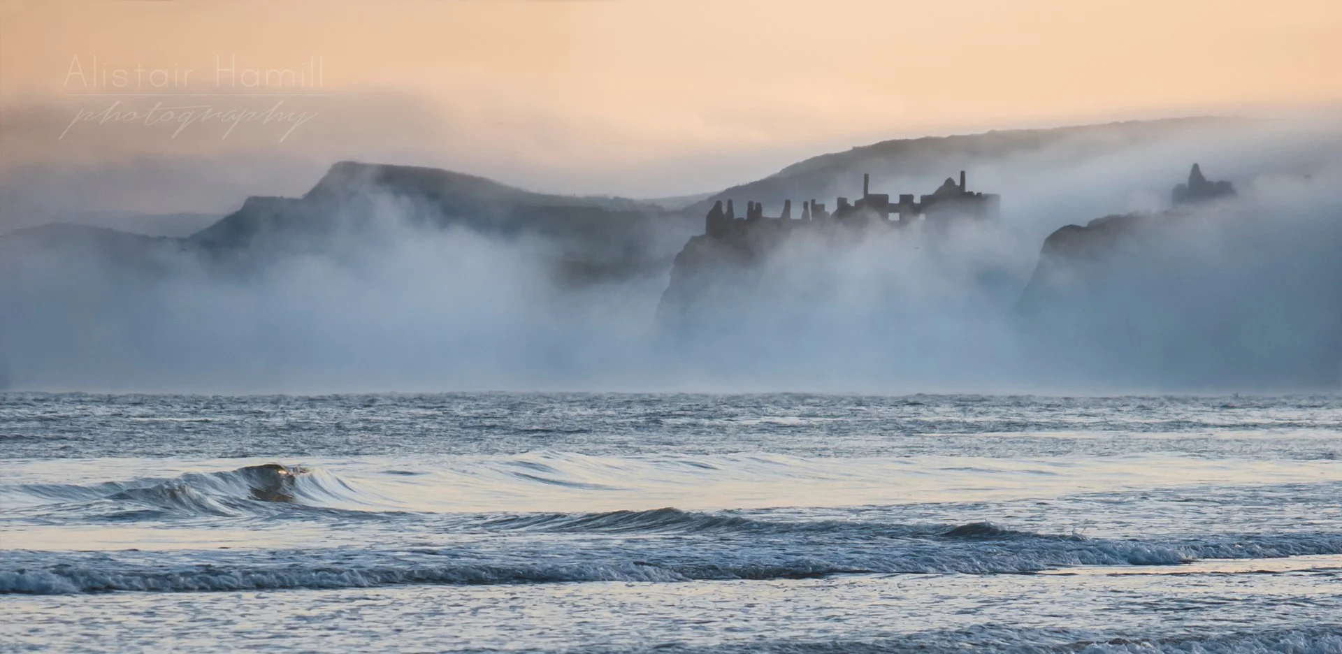 Dunluce Castle finally and briefly emerges from the early morning fog.