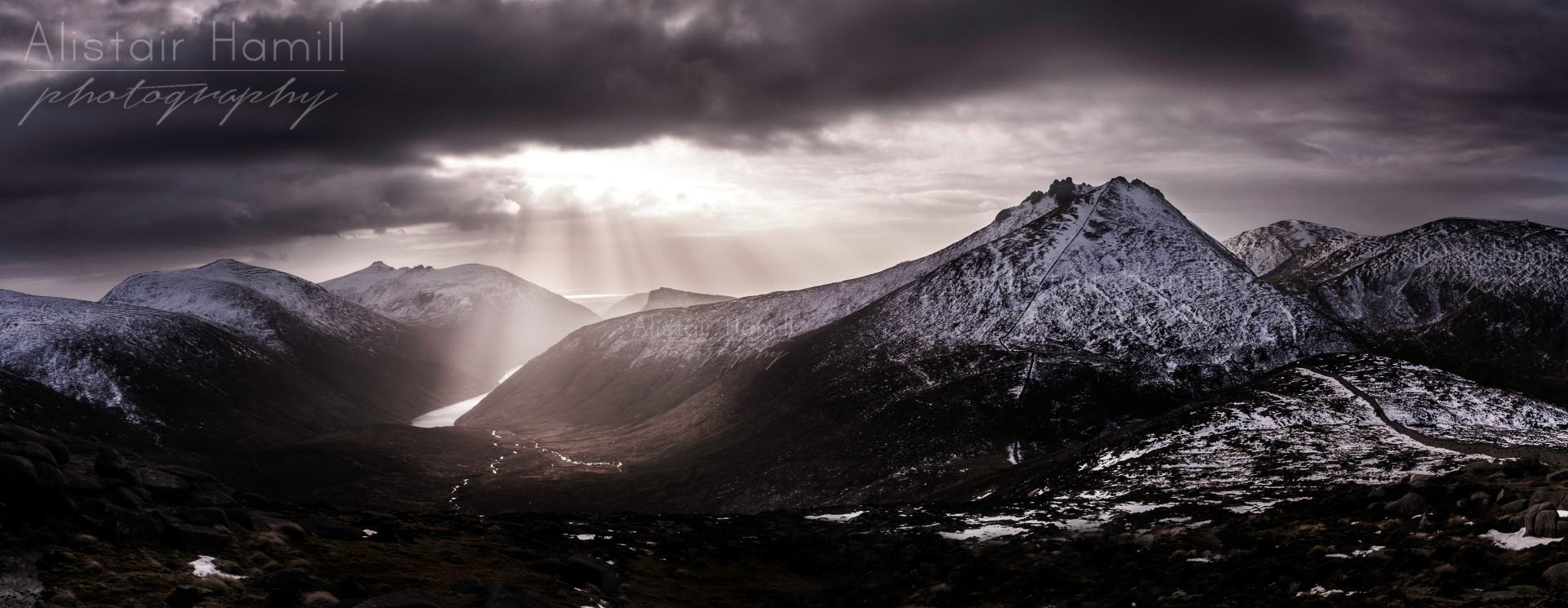 The summit of Bearnagh rises majestically over Ben Crom valley, bathed in the shafts of some winter light.