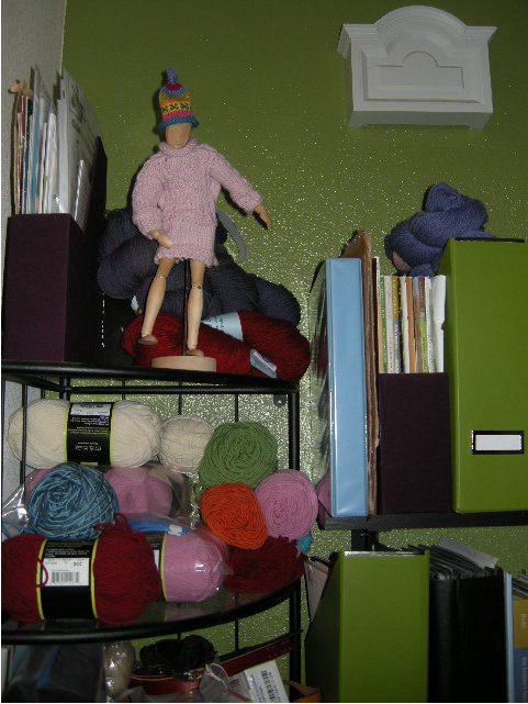 My most-often referenced books, patterns and materials all live near where I write. On the top shelf is Woody, my artist's model, sporting a miniature gansey I made in class, as well as a wee hat. Woody provides the constant supervision required by my kind of behavior.