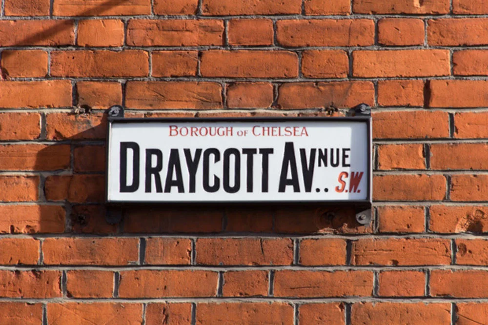 “In 1899 the London Government Act divided London into twenty-eight Metropolitan Boroughs, which lasted until 1965 with the creation of Greater London and the thirty-two London Boroughs which we know today. Signs from the Metropolitan Boroughs still exist in many parts of London though, such as this Borough of Chelsea sign. Postal districts were created in 1857, but weren’t numbered until 1917. So it seems likely that this sign dates from between 1899 and 1917. The lettering of the street name and postal district is of a style that seems quite specific to signage, especially enamel signs (though this sign is milk-glass not enamel). It’s a condensed sans that features angled terminals on certain letters – the C, G, J and S – but I haven’t yet found out where it originates from.”