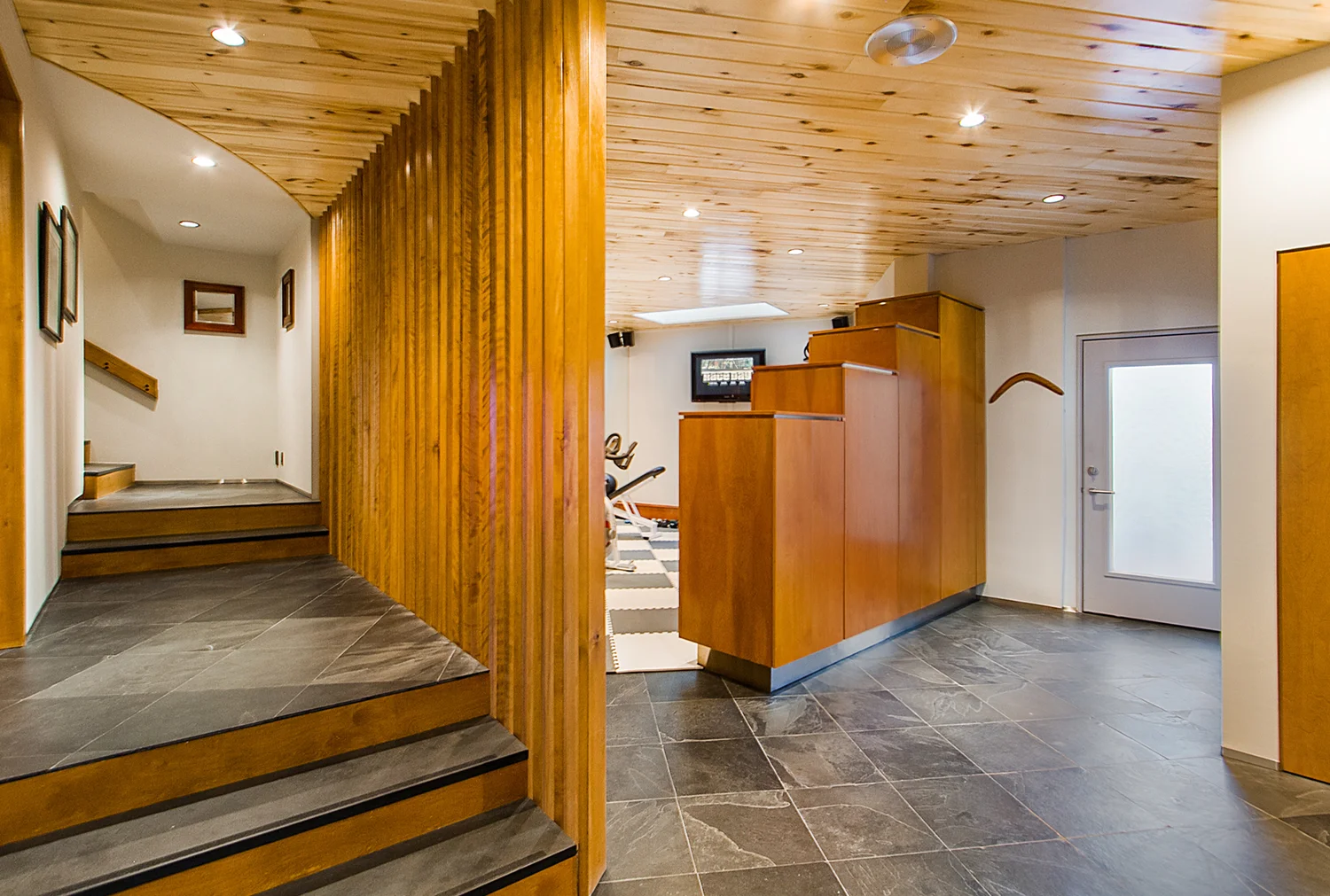 Lower level entry with new doors, custom cabinetry, trim with stainless steel detailing, louvered walls, new aspen ceiling and Vermont Slate floors