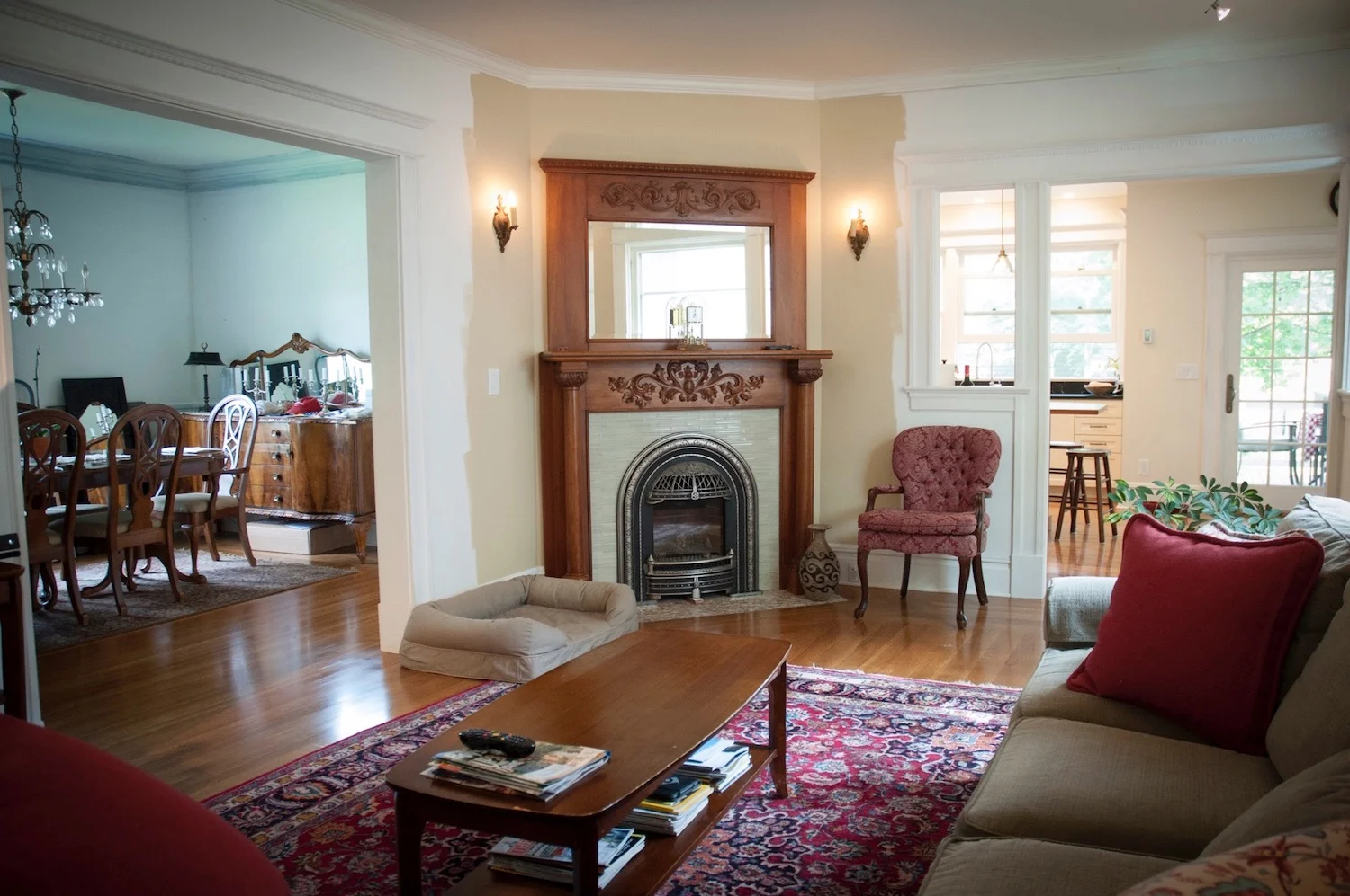 After: A new doorway to the kitchen and a wider doorway to the dining room provides better circulation and shares light between the rooms. An antique heirloom mantle and vintage gas insert bring the fireplace back to life.