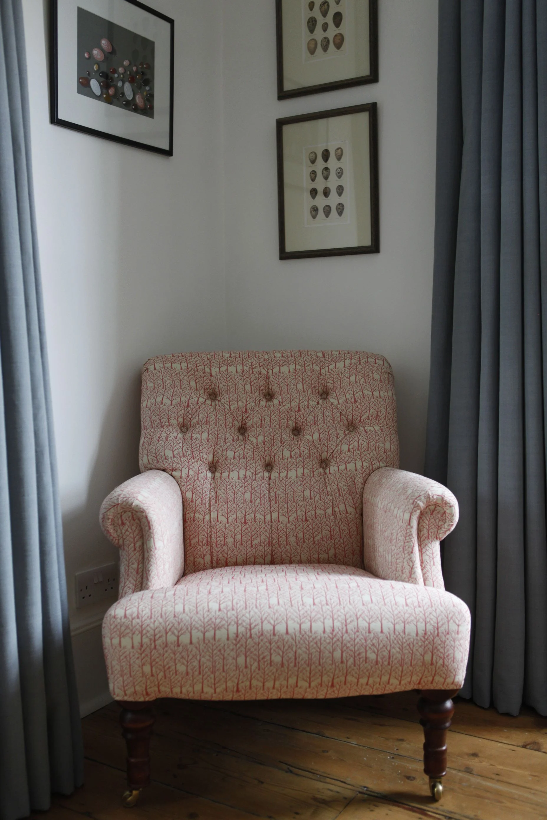 Chair in a coral coloured fabric and cool blue curtains