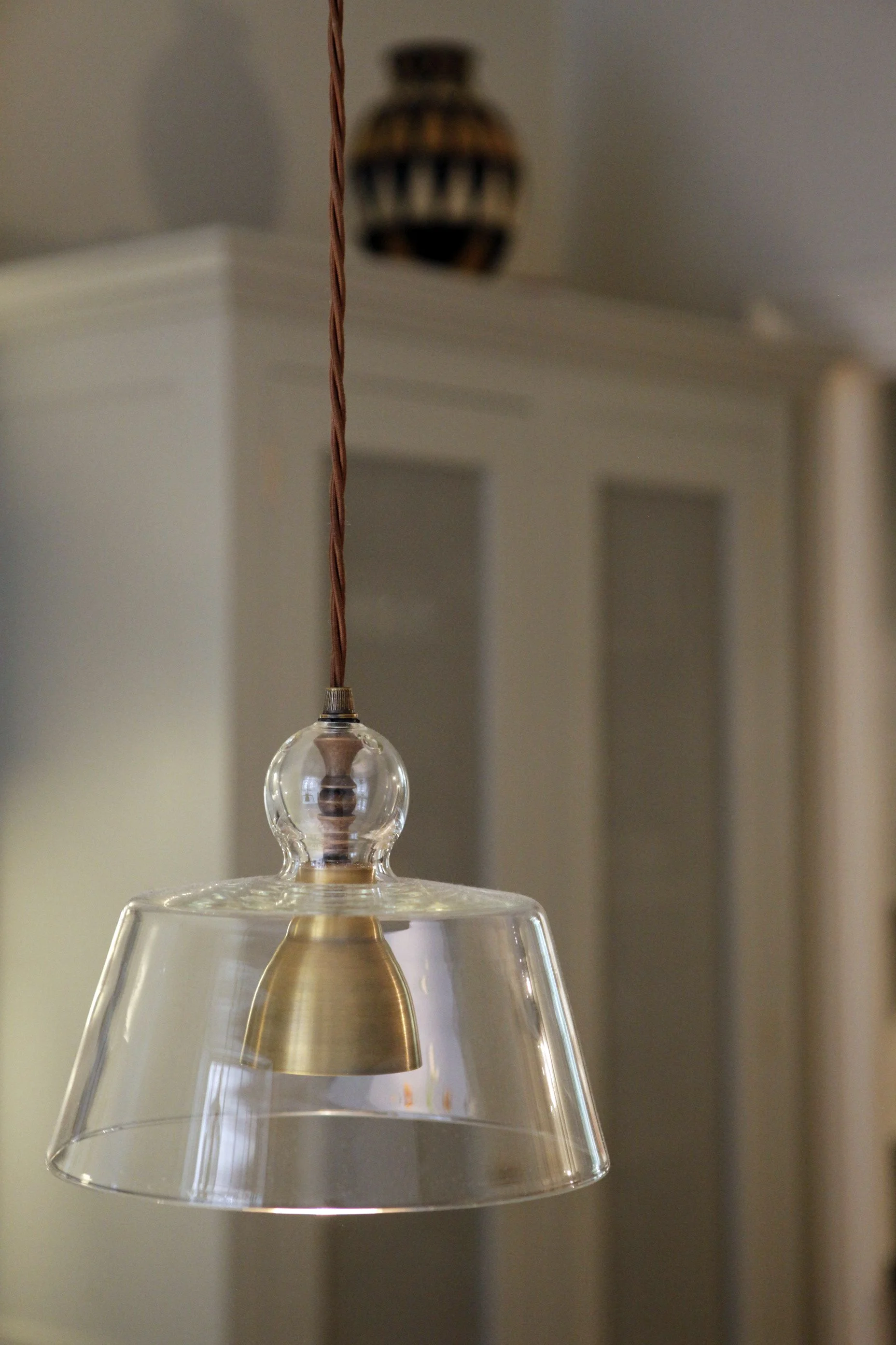 A Colombian water container sits above an armoire in a pale grey/green tone