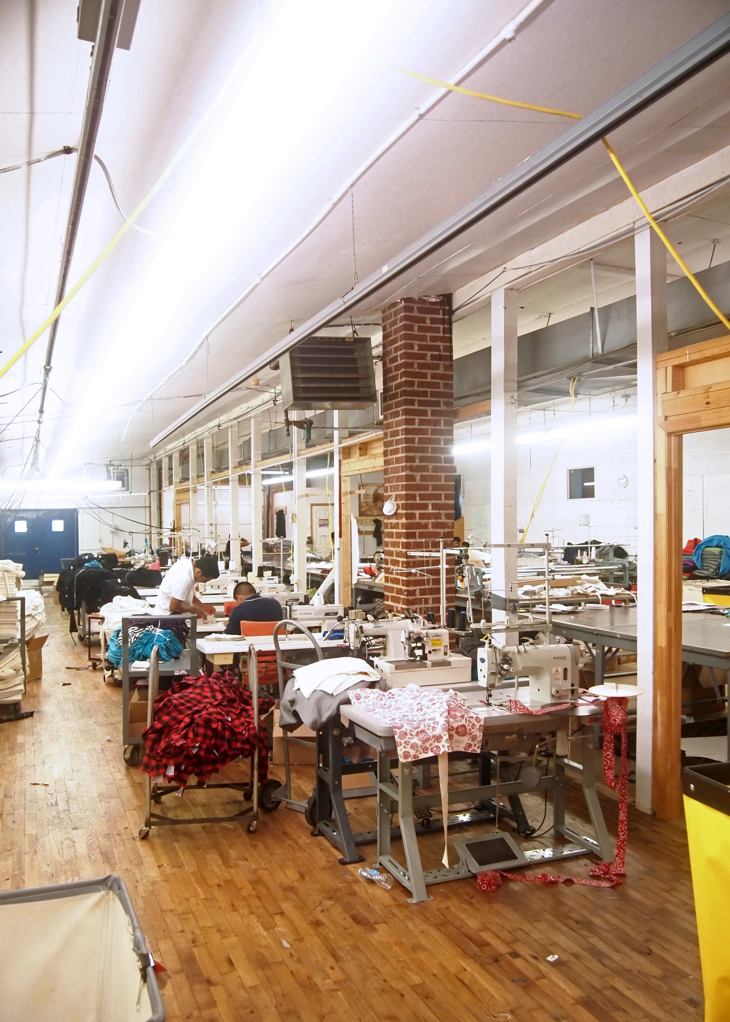Two sewers work on the BWS hip pouches at Opportunity Threads.